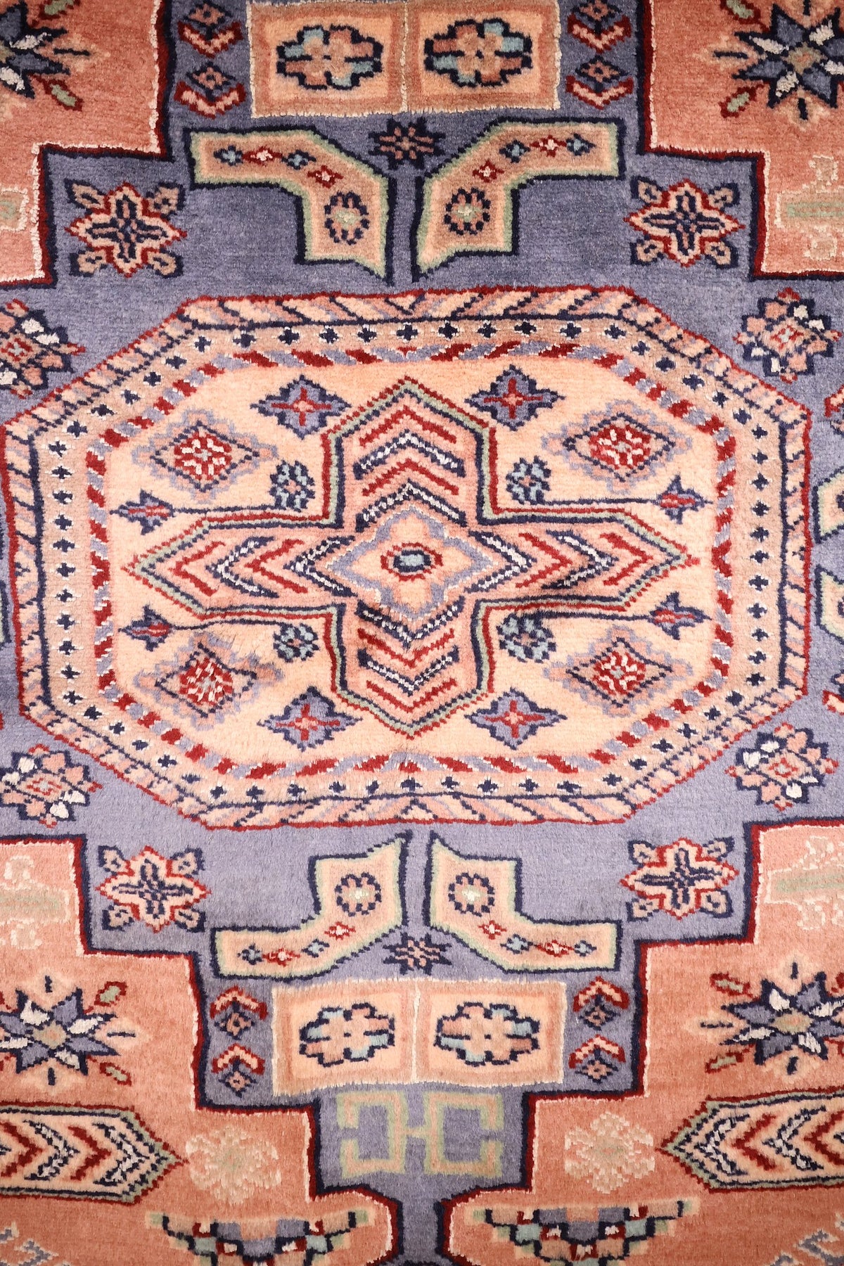 Détail du médaillon octogonal bleu-gris à cœur clair du tapis Caucase rose