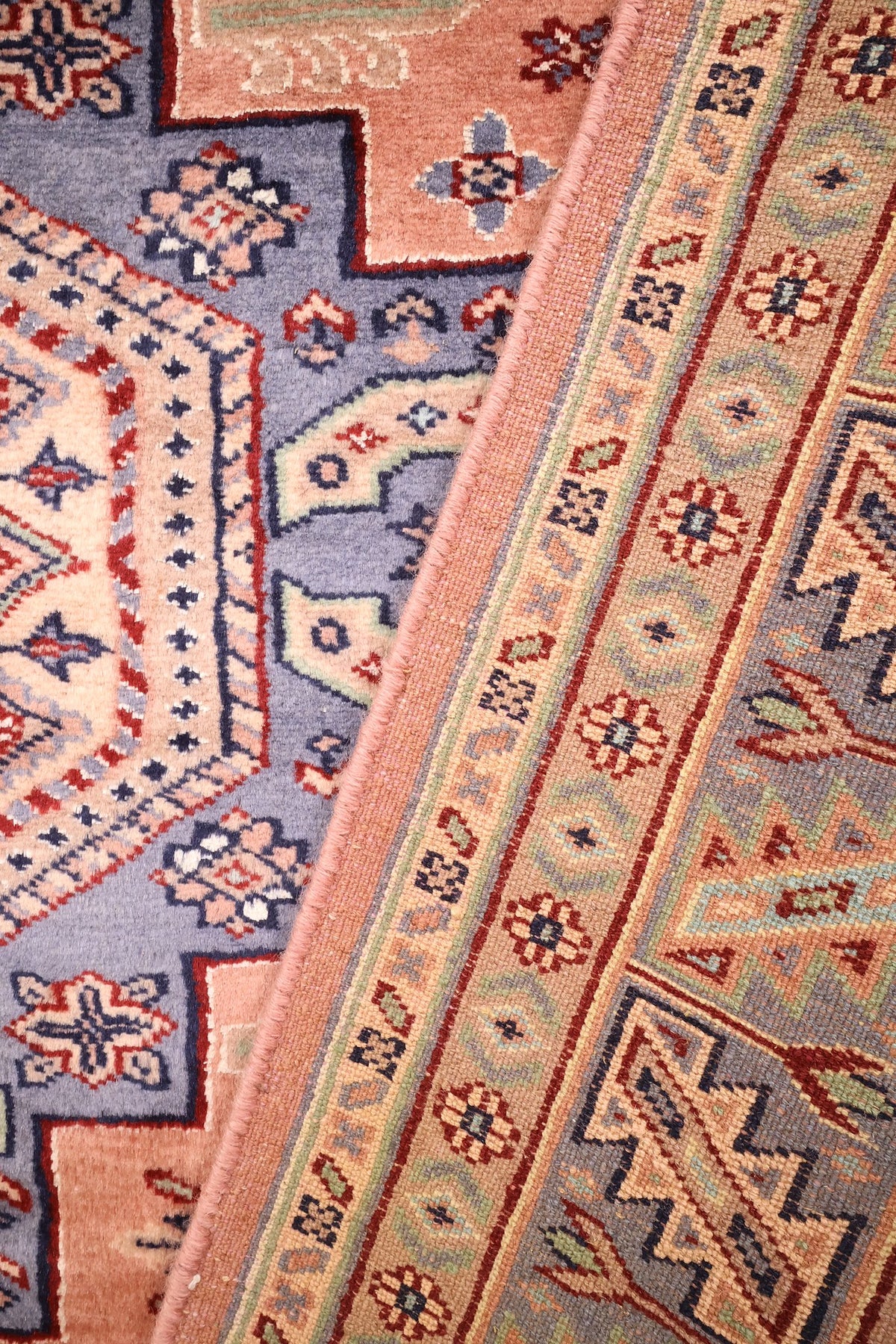 Coin replié du tapis Caucase 184 × 124 cm, bordure et champ rose saumon