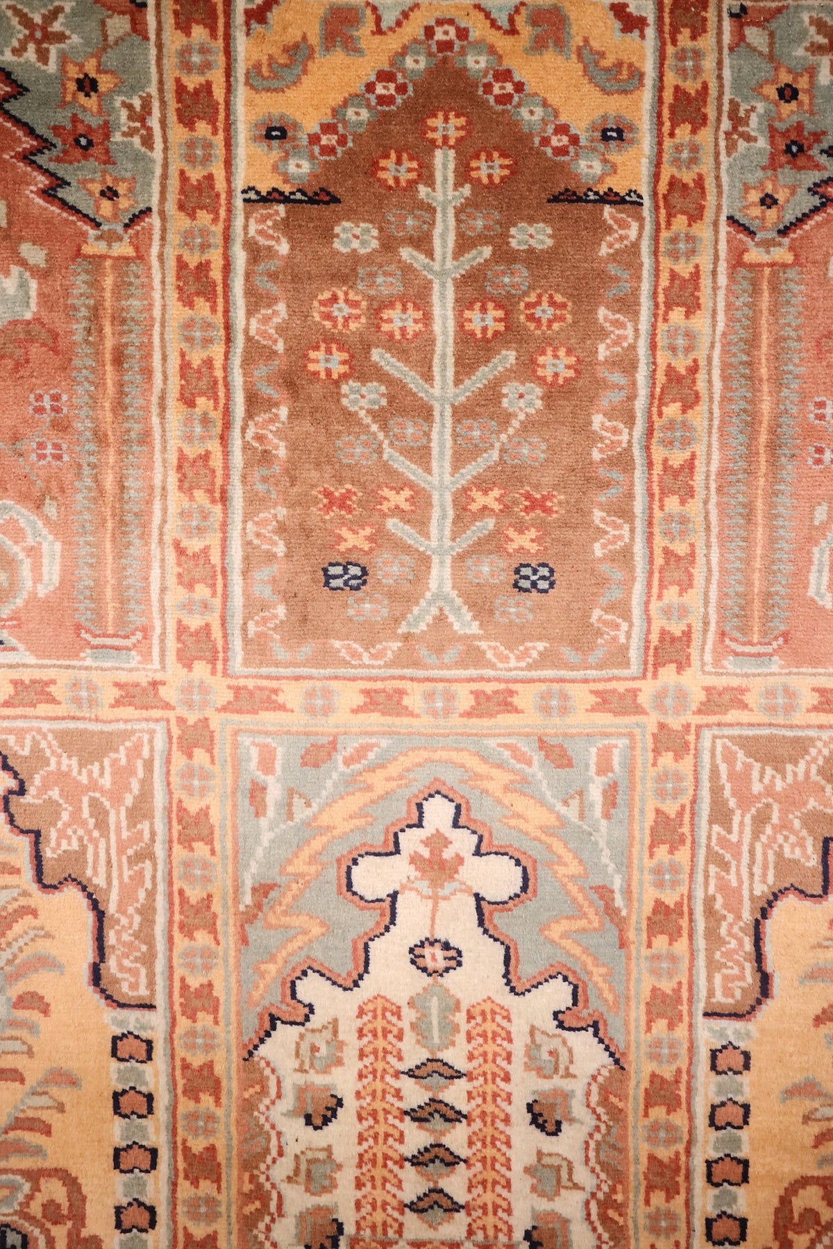 Détail des arbres de vie sur fonds brun et abricot du tapis Caucase rose