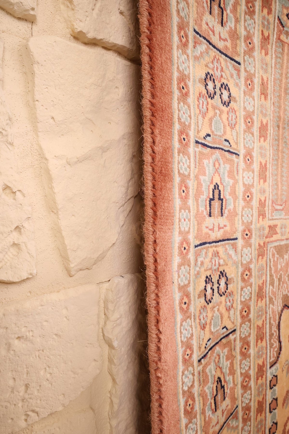 Lisière rose du tapis Caucase noué à la main, le long du mur
