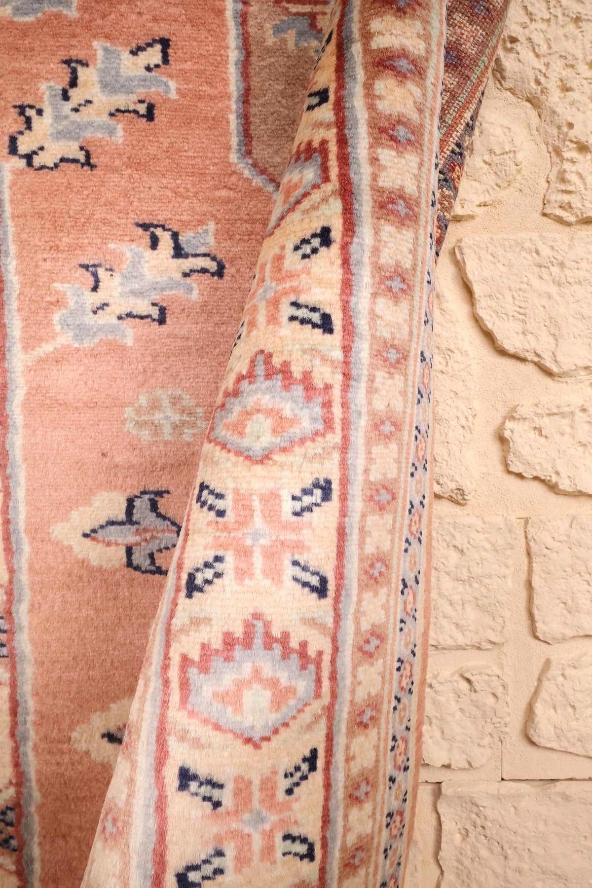 Coin replié du tapis Caucase rose, épaisseur de laine et fleurons crochetés