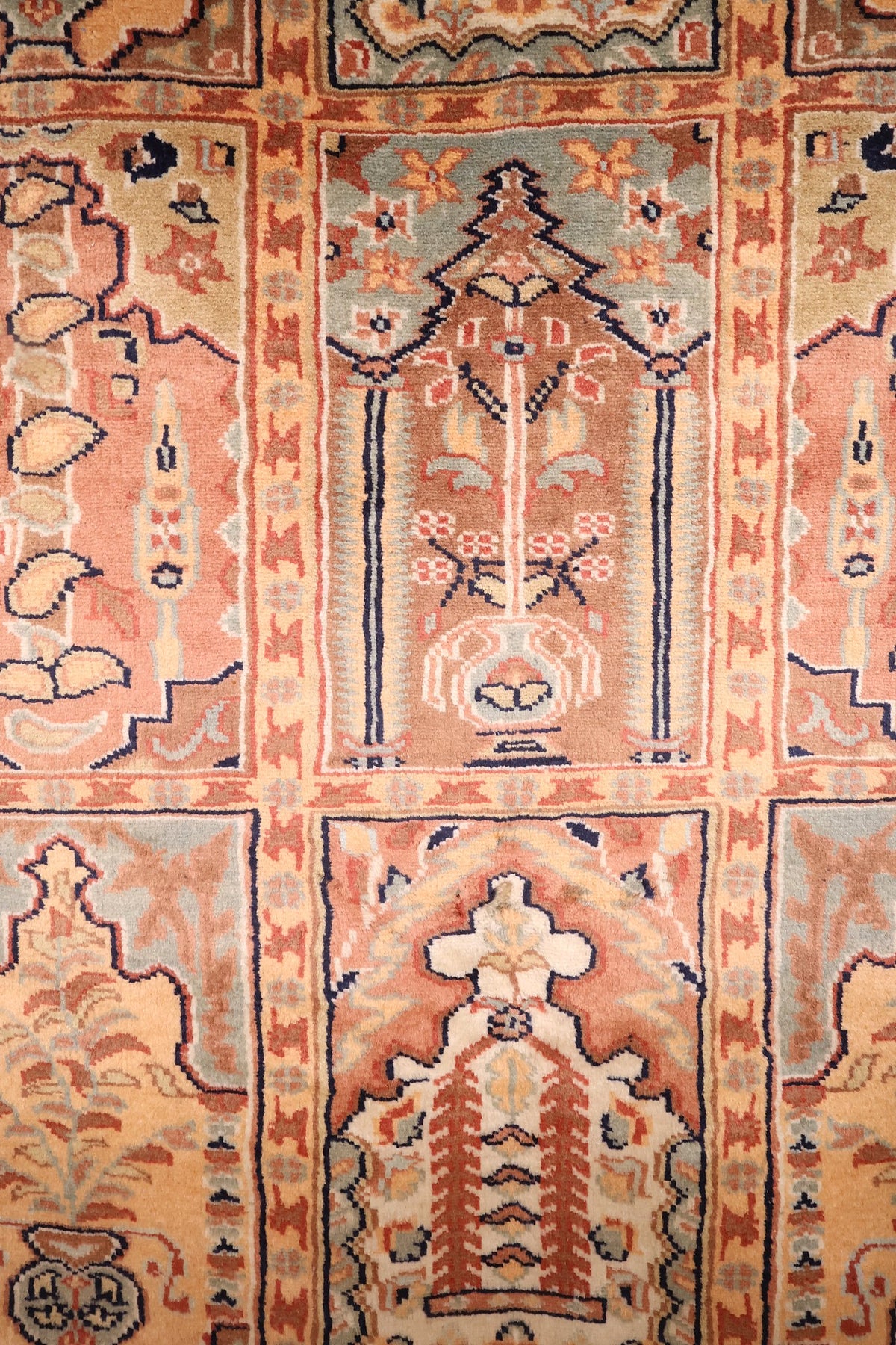 Détail des arbres stylisés et vases sous arche du tapis Caucase rose et orange