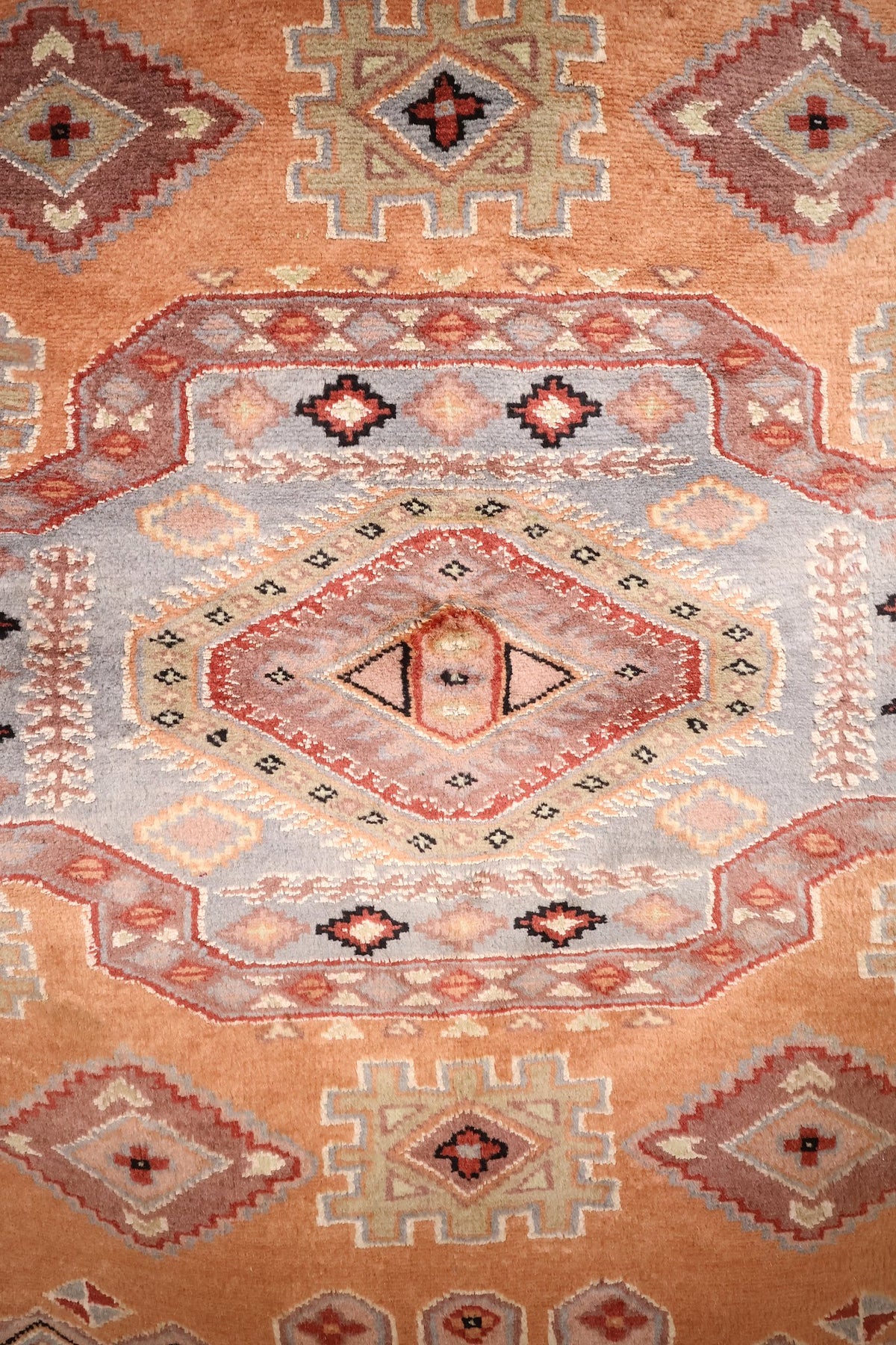 Détail du médaillon bleu à losange rouge du tapis Caucase orange