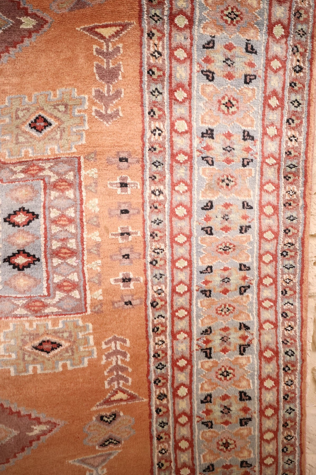 Bordures bleu et beige à rosettes et crochets noirs du tapis Caucase