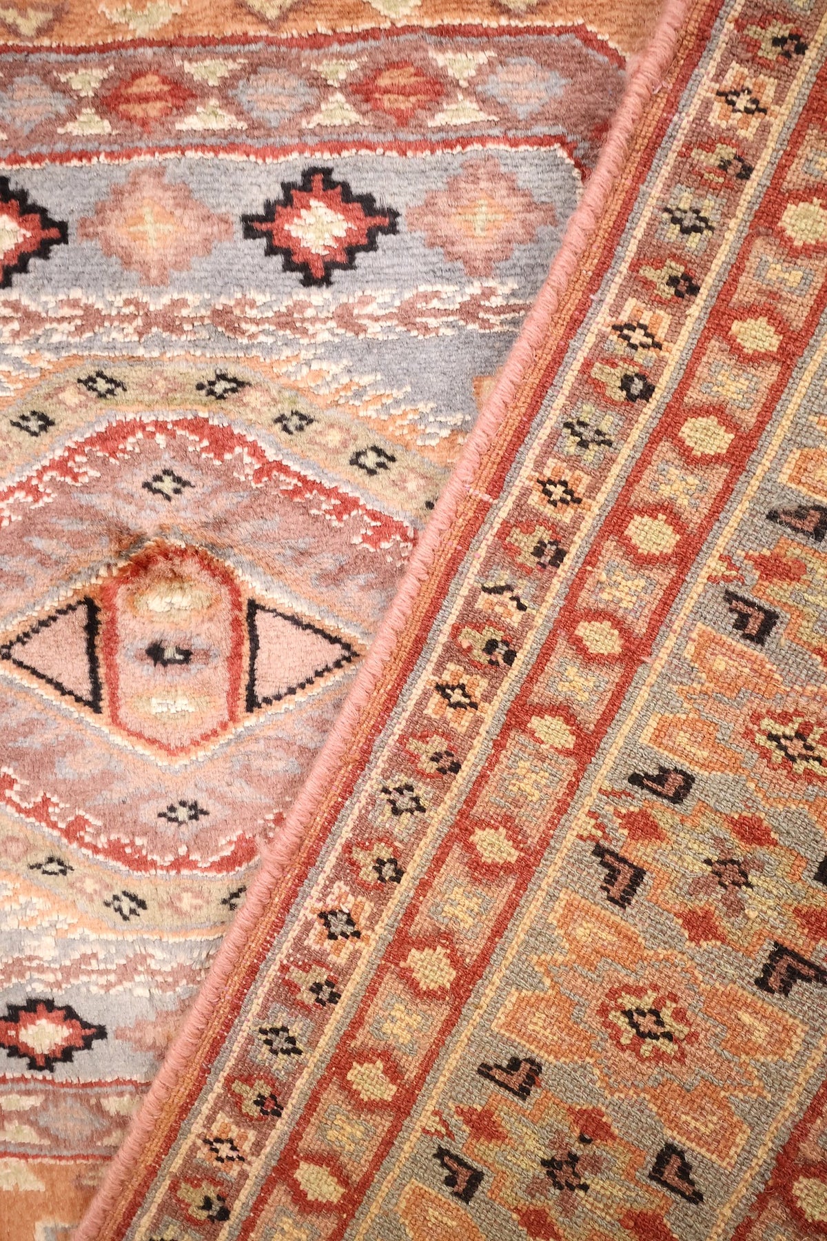 Coin replié du tapis Caucase, losanges crénelés et fines bandes rouges