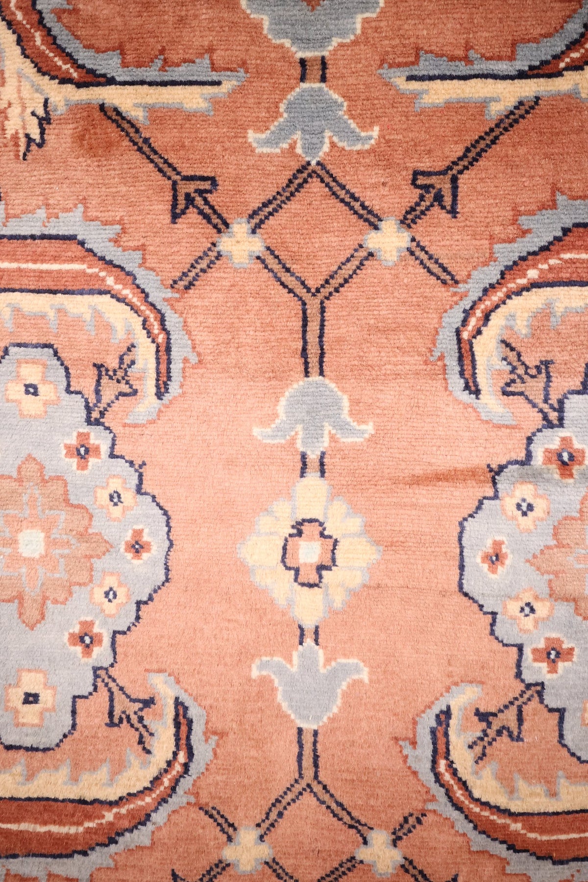 Détail des rosaces bleu-gris et ivoire sur le champ rose du tapis Caucase