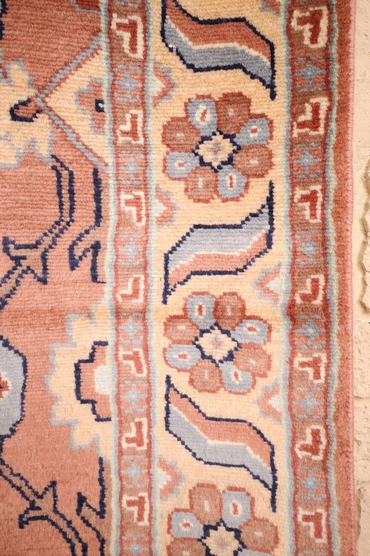 Bordure beige à rosaces et feuilles recourbées, contre-bordures rouge-brun à crochets