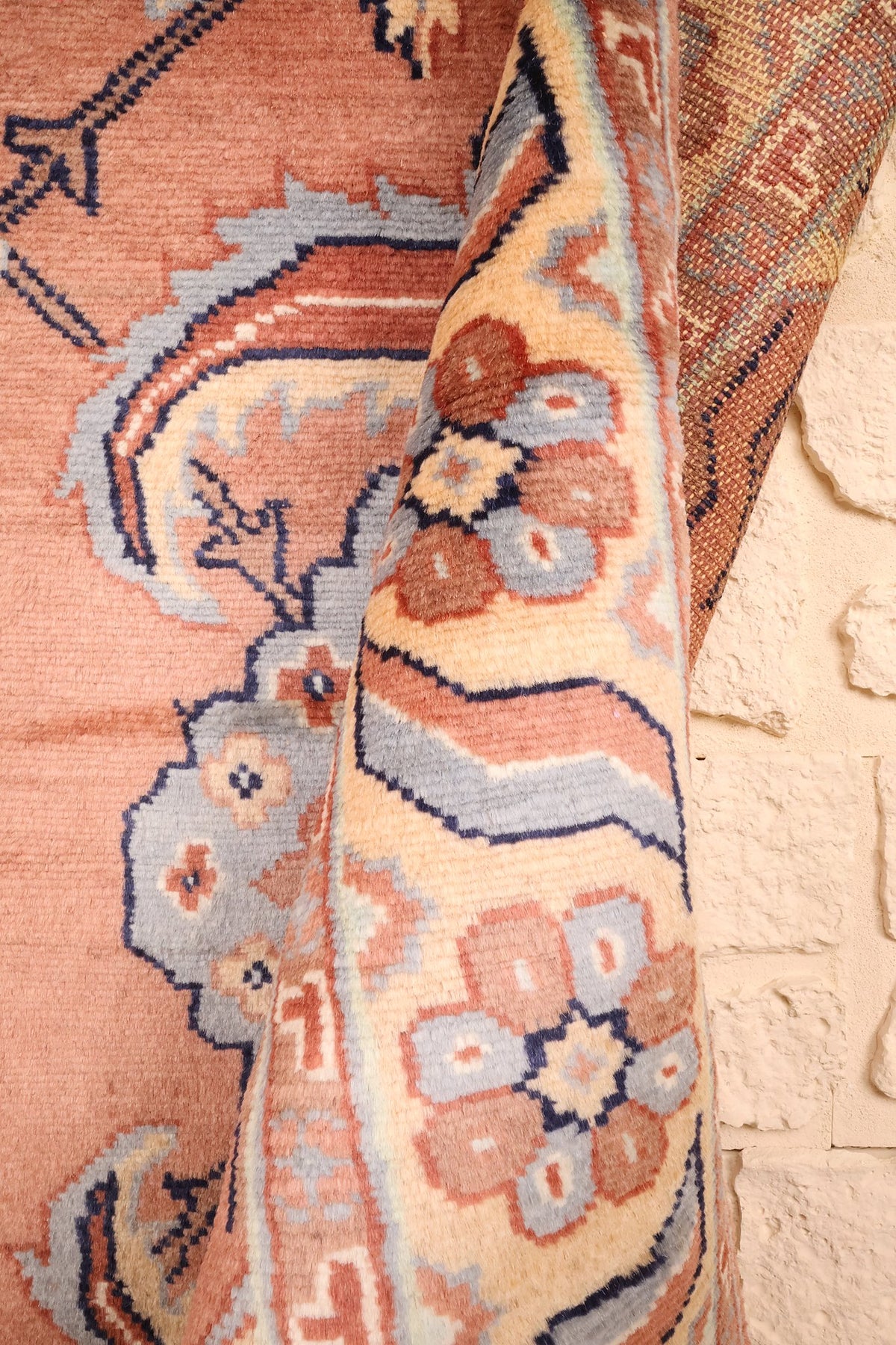 Coin replié du tapis Caucase rose, épaisseur de la laine et envers entrevu
