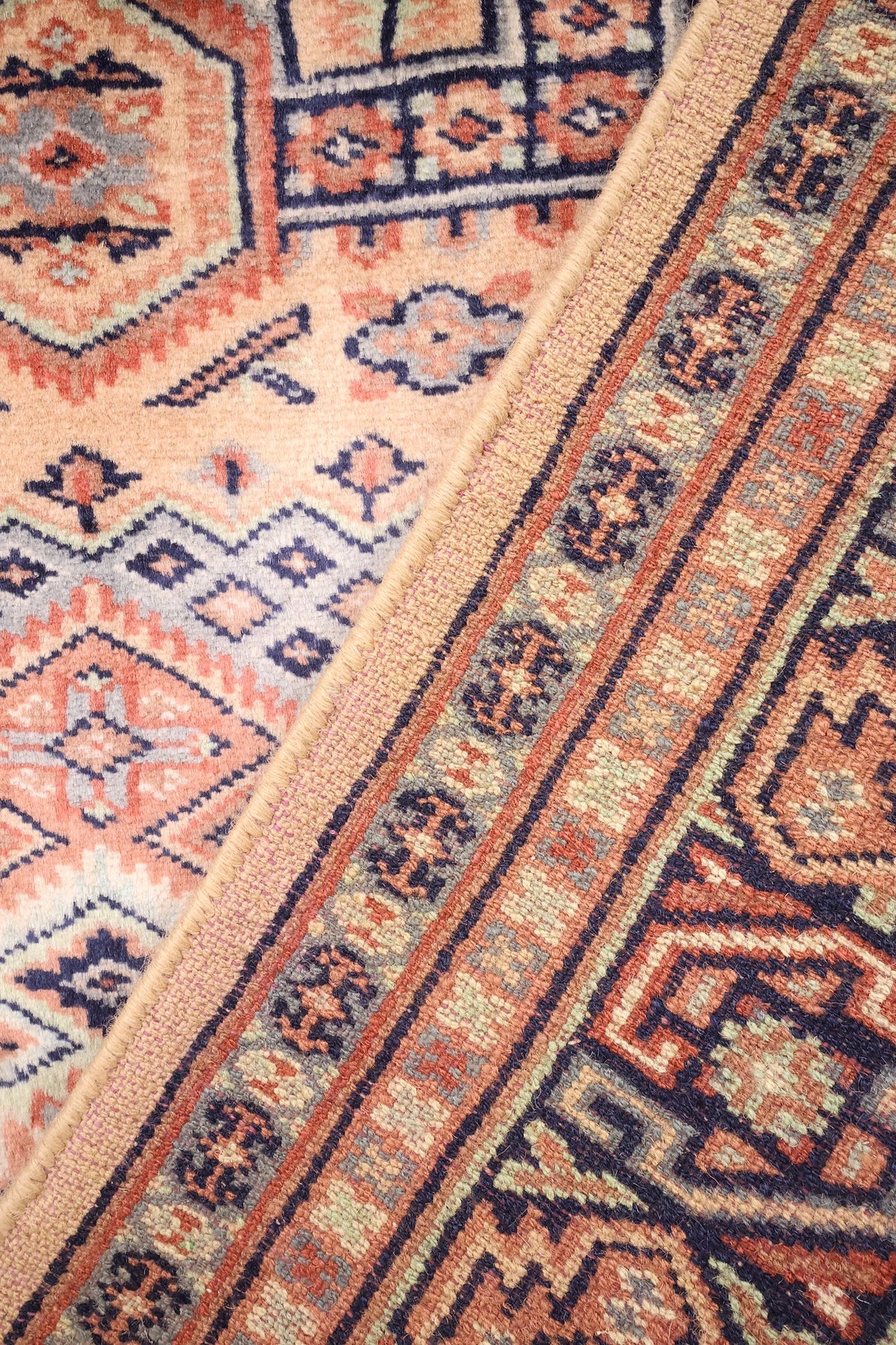 Coin replié du tapis Caucase beige, laine nouée main et dos visible