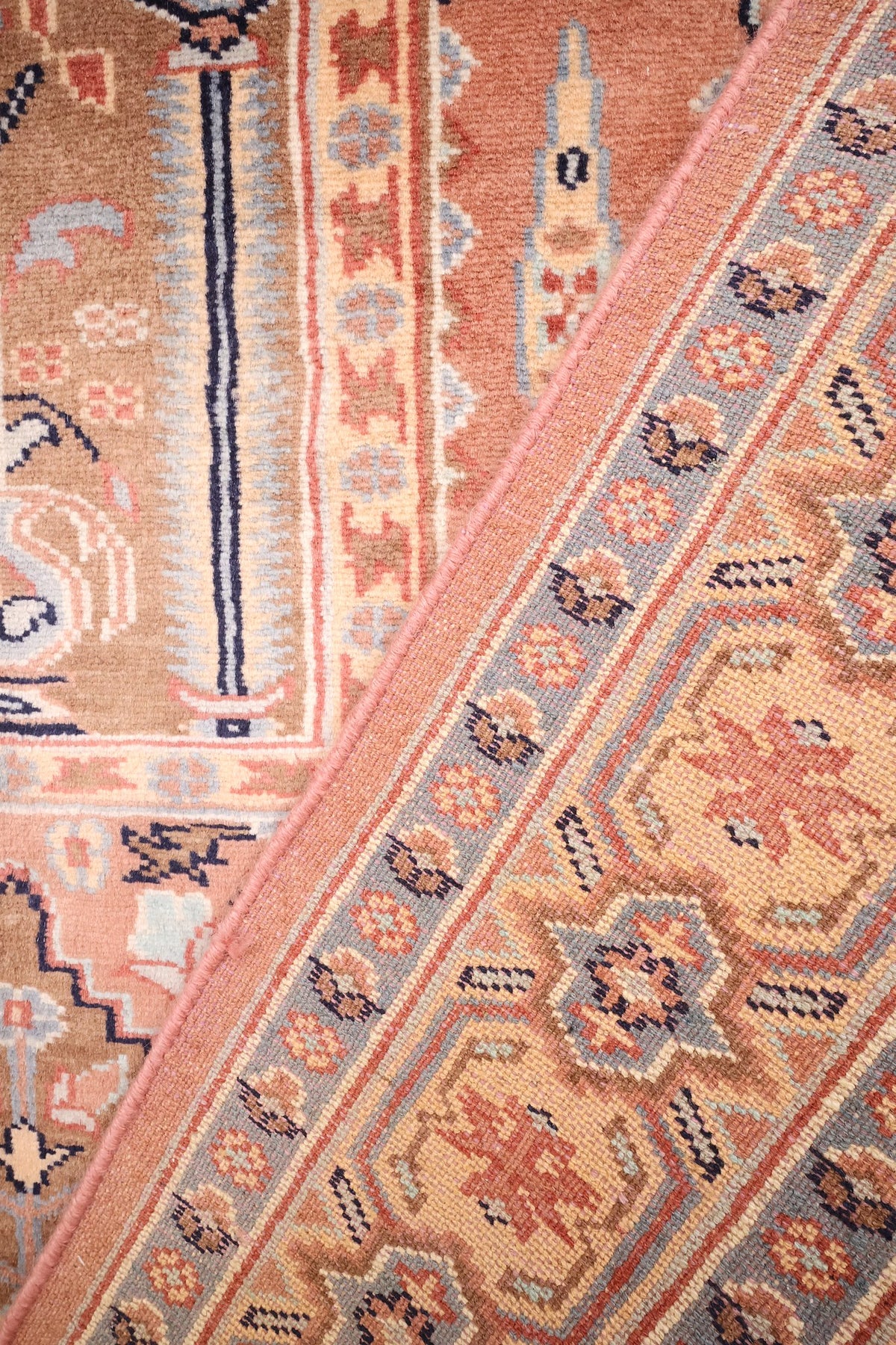 Coin replié du tapis rectangulaire 195 × 124 cm, motifs rose et bleu de près