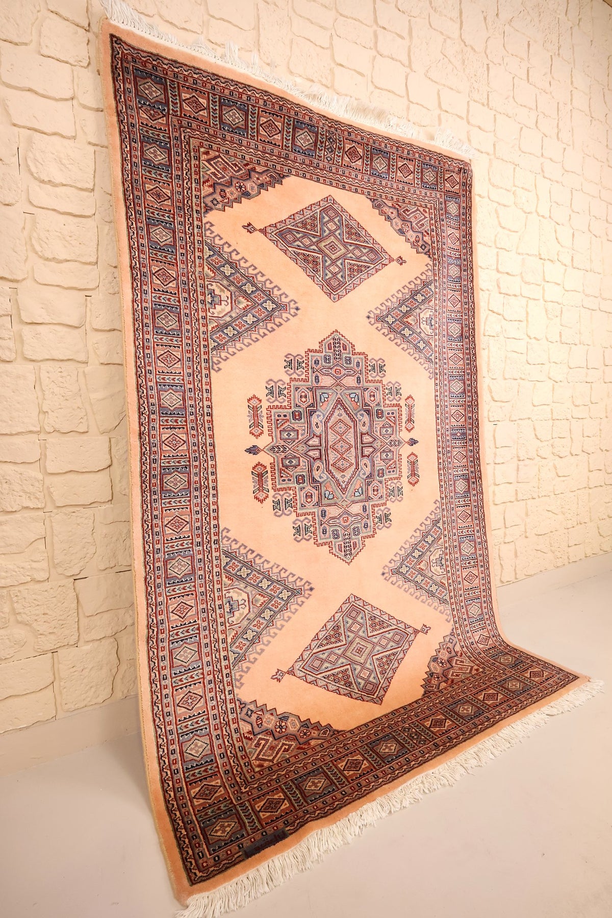 Tapis Caucase en laine noué à la main, vue de biais sur le champ rose saumon