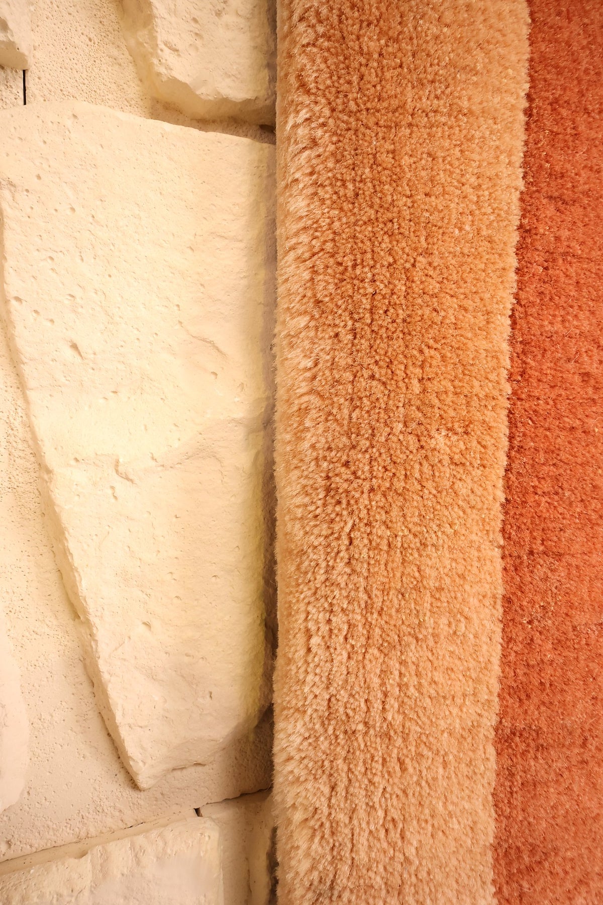 Lisière beige du tapis Chinois orange contre un mur de pierre claire