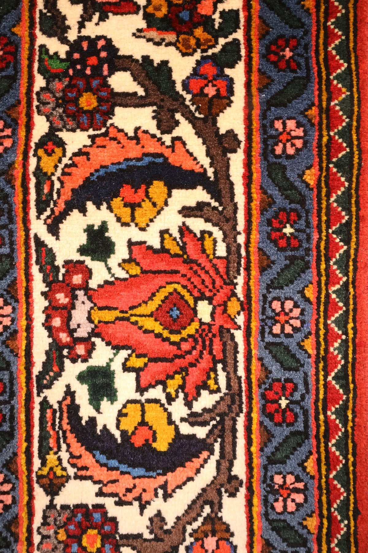 Bordure ivoire du tapis Djahad, grandes palmettes rouges et contre-bordure bleue fleurie