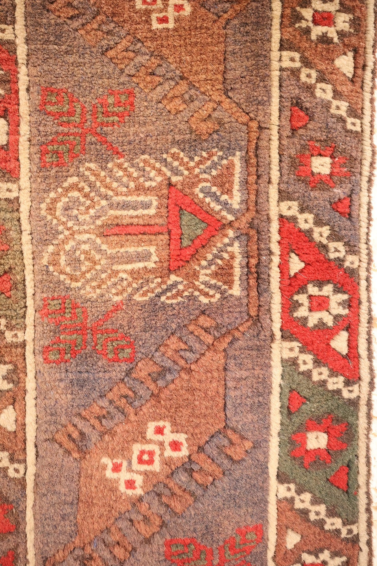 Bordures brun-mauve et grises du tapis Dodgem Alti, médaillons crochus et étoiles ivoire