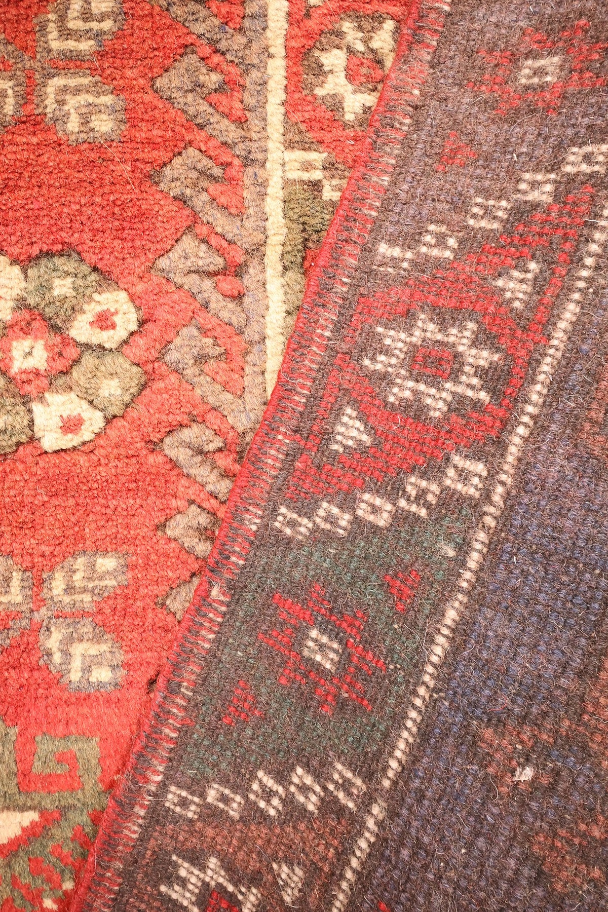Coin replié du tapis Dodgem Alti rouge, envers aux nœuds serrés et bordure étoilée