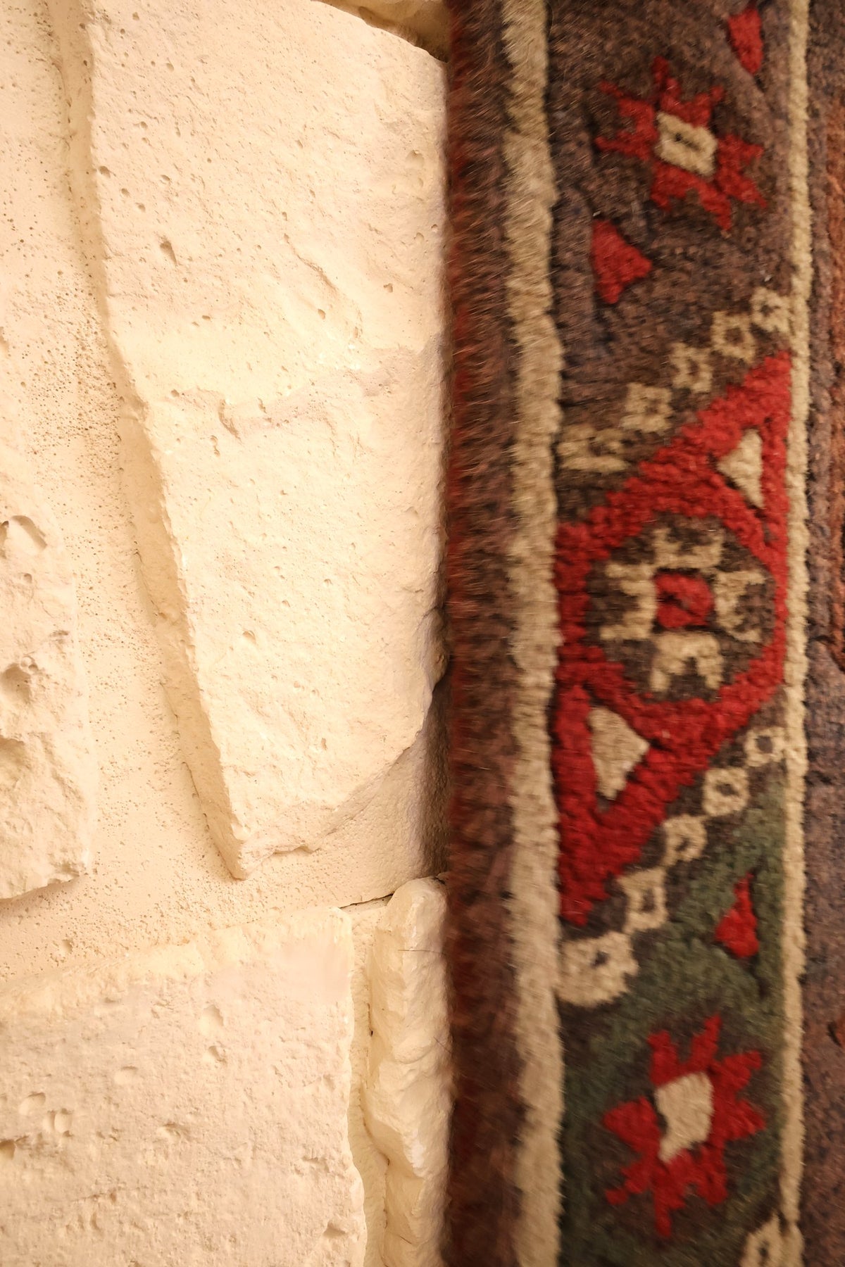 Lisière du tapis Dodgem Alti rouge et beige contre le mur, triangles et étoiles de bordure