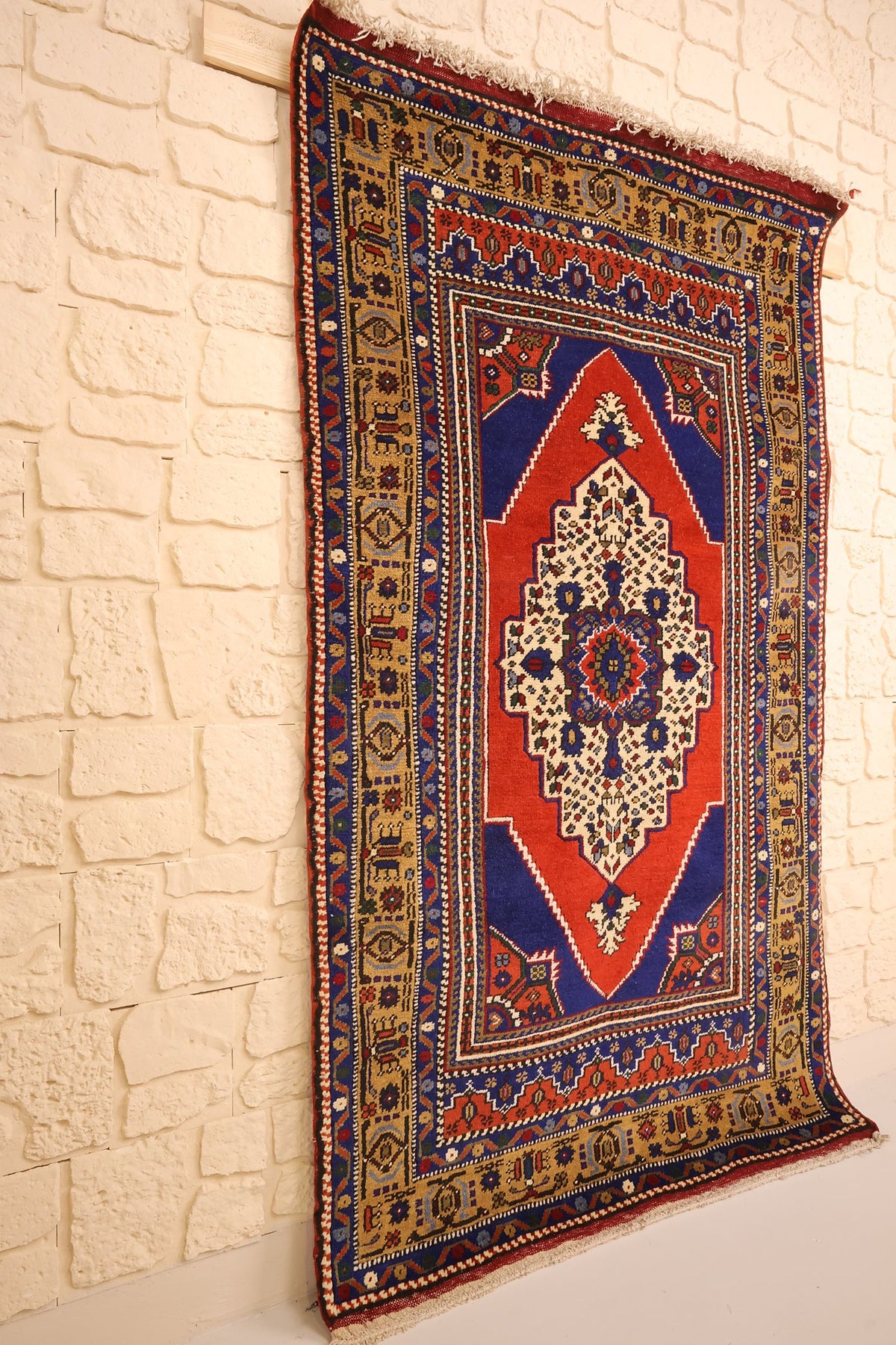 Tapis Dodgem Alti rectangulaire à dominante bleue, vue de biais contre un mur clair