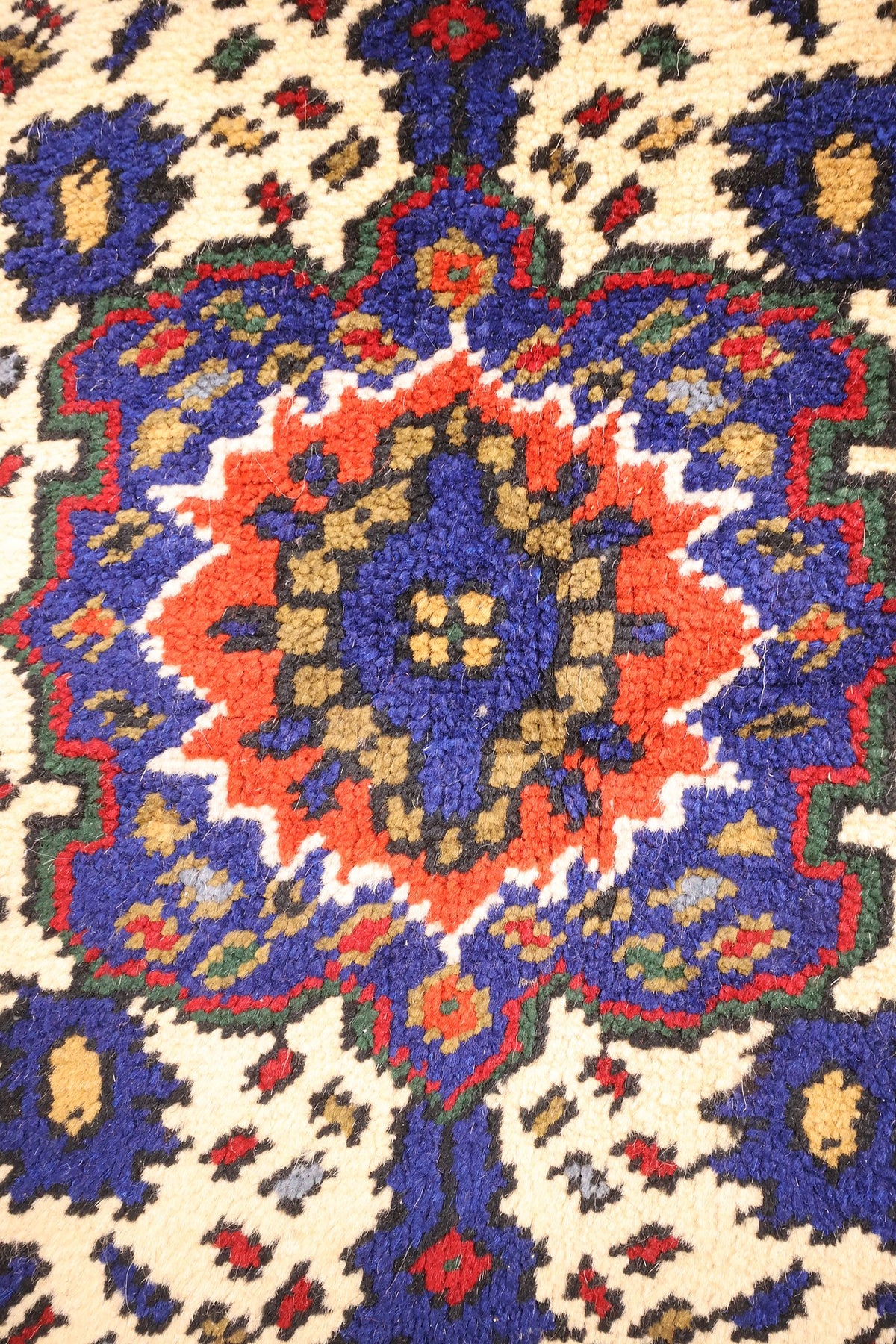 Détail de la rosace orange et bleue au centre du médaillon ivoire du tapis Dodgem Alti