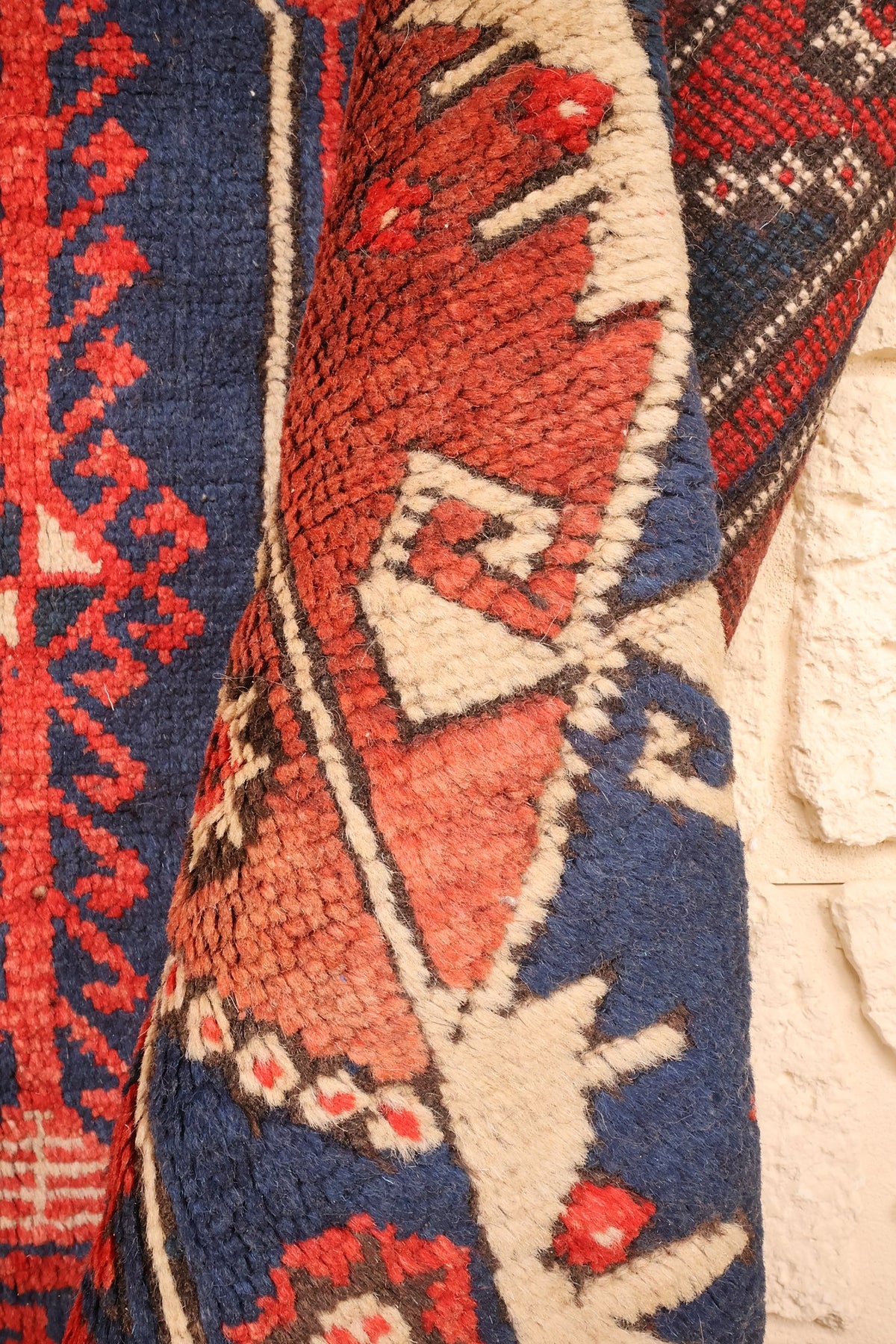 Coin replié du tapis Dodgem Alti rouge et bleu, épaisseur et motifs crantés de la bordure