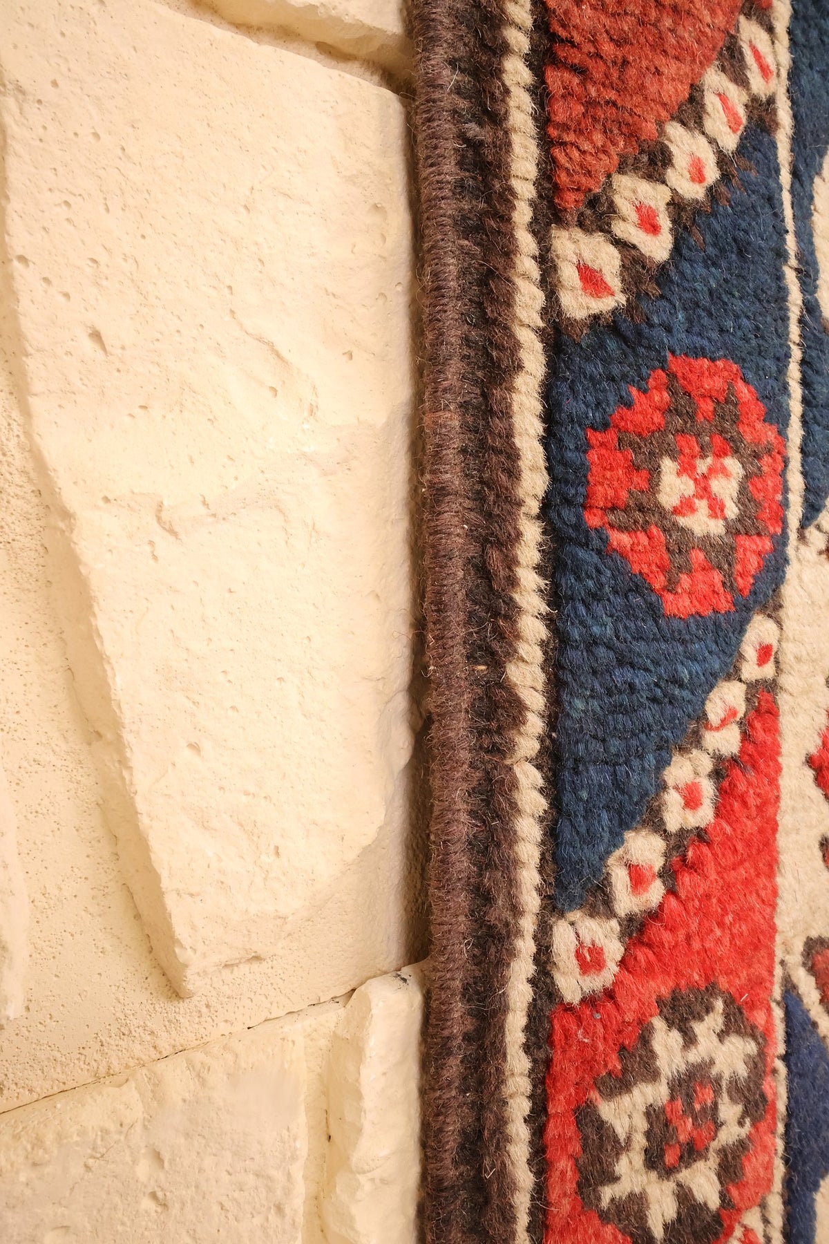 Lisière brune du tapis Dodgem Alti le long de la bordure bleue à rosettes rouges