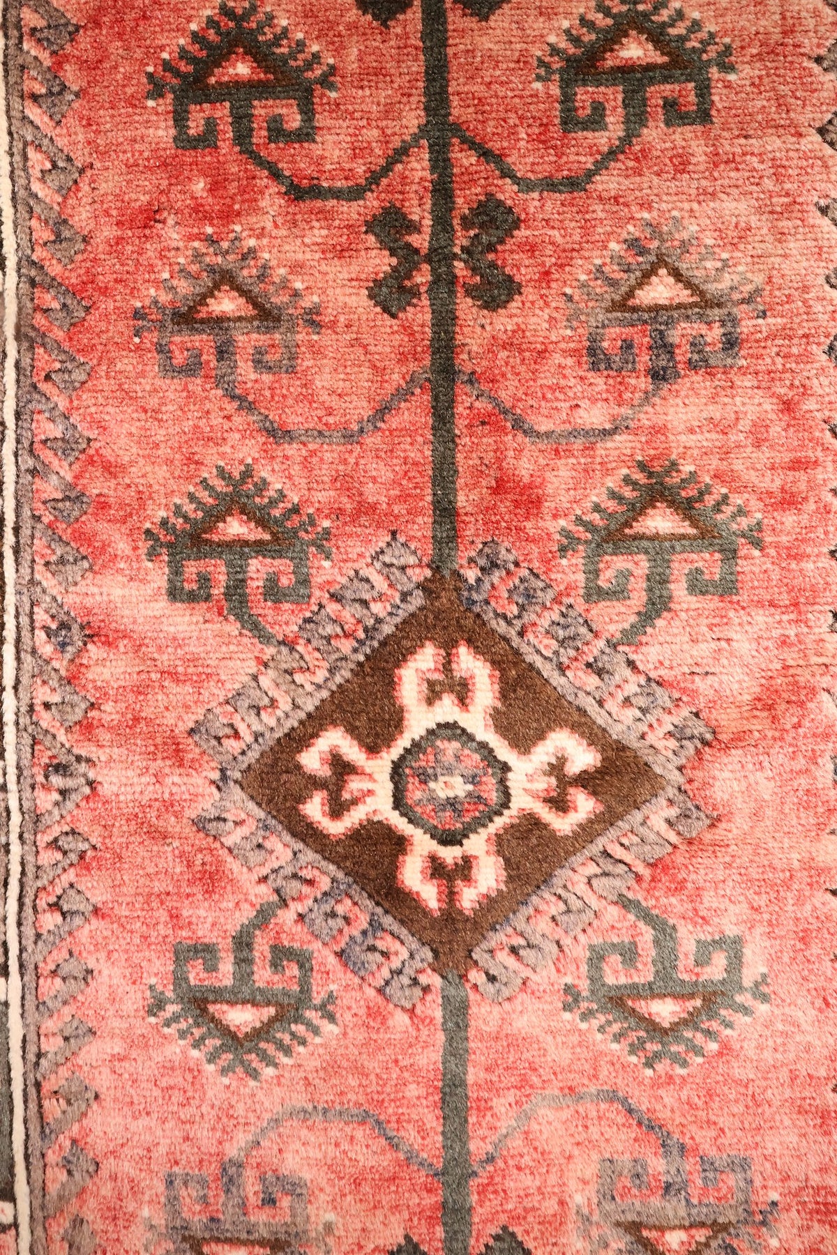 Détail du médaillon en losange marron à cœur crème et bleu sur champ rose