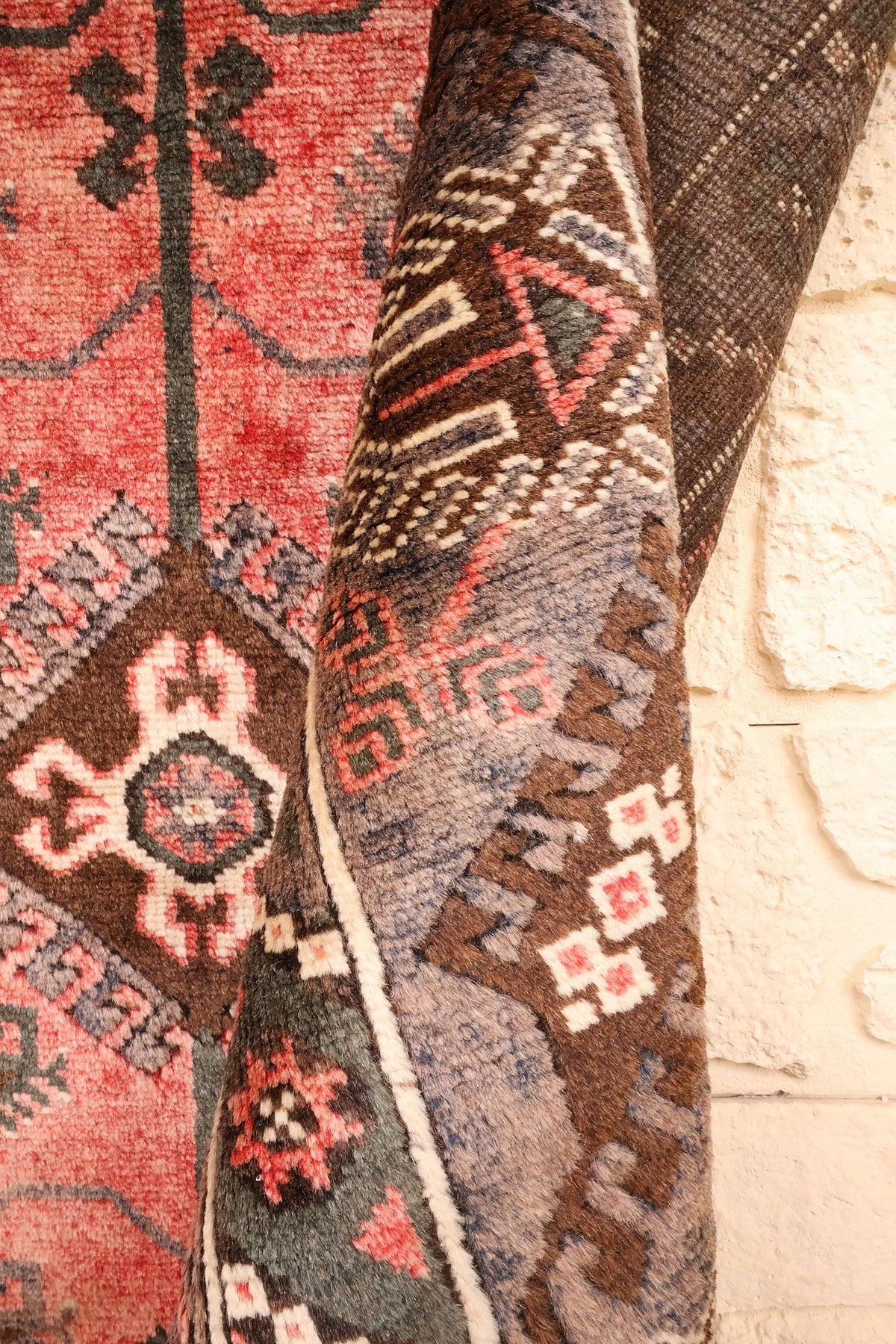 Tapis Dodgem Alti rose et gris replié, épaisseur et bordure anguleuse crochetée visibles