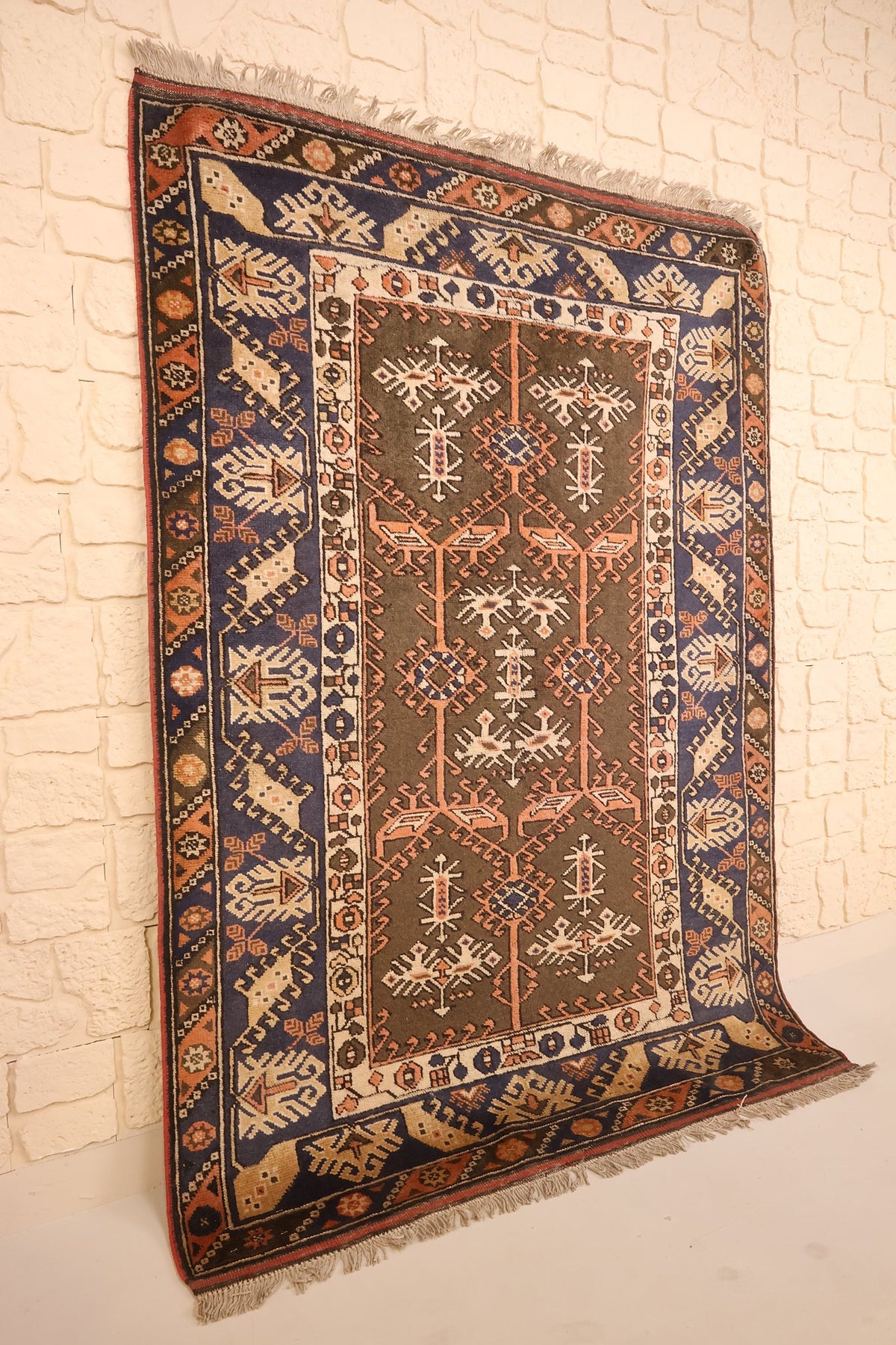 Tapis Dodgem Alti marron et bleu vu de biais, bordure bleue et motifs orange saumon