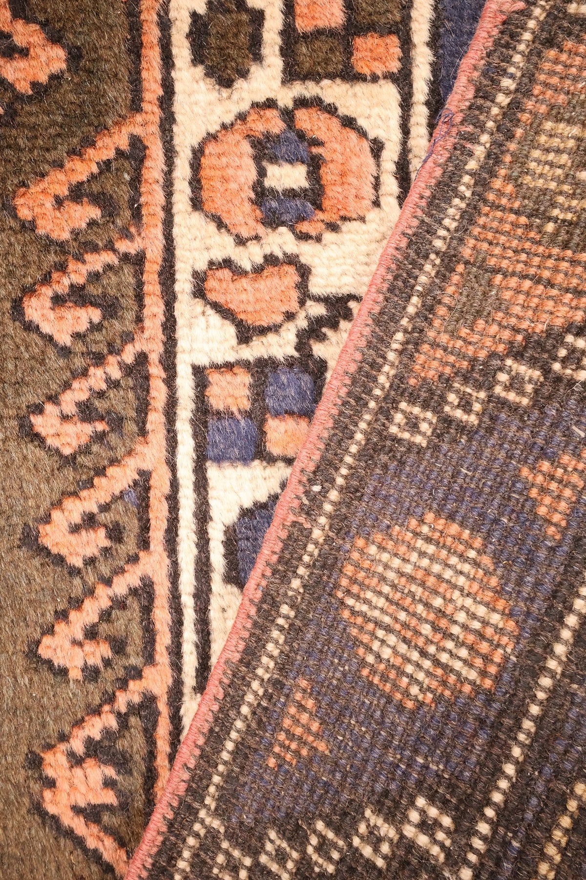 Coin replié du tapis Dodgem Alti marron, contre-bordure ivoire et dos visible