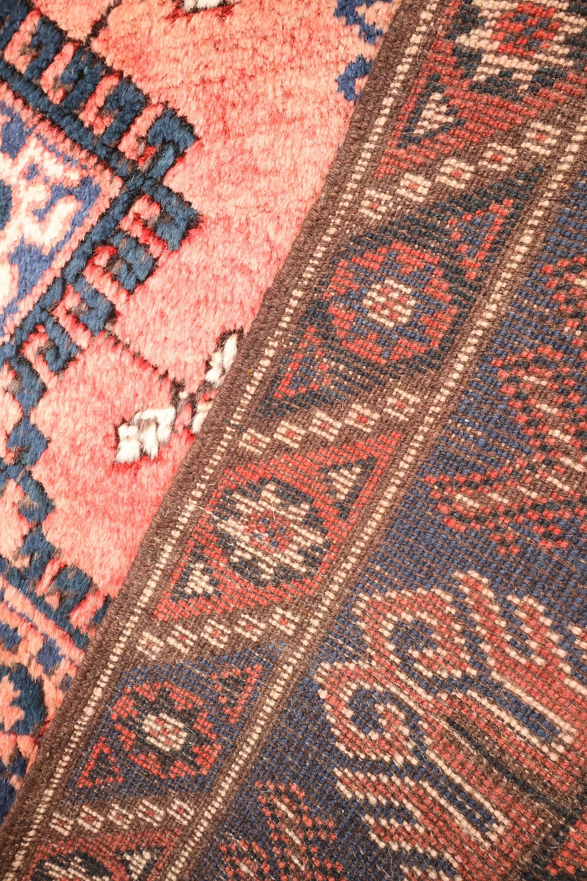 Envers du tapis Dodgem Alti, nœuds visibles sur la bordure bleue et rose