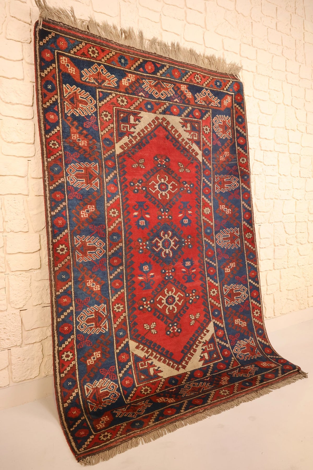 Tapis Dodgem Alti rectangulaire rouge et bleu posé contre un mur, vue de biais