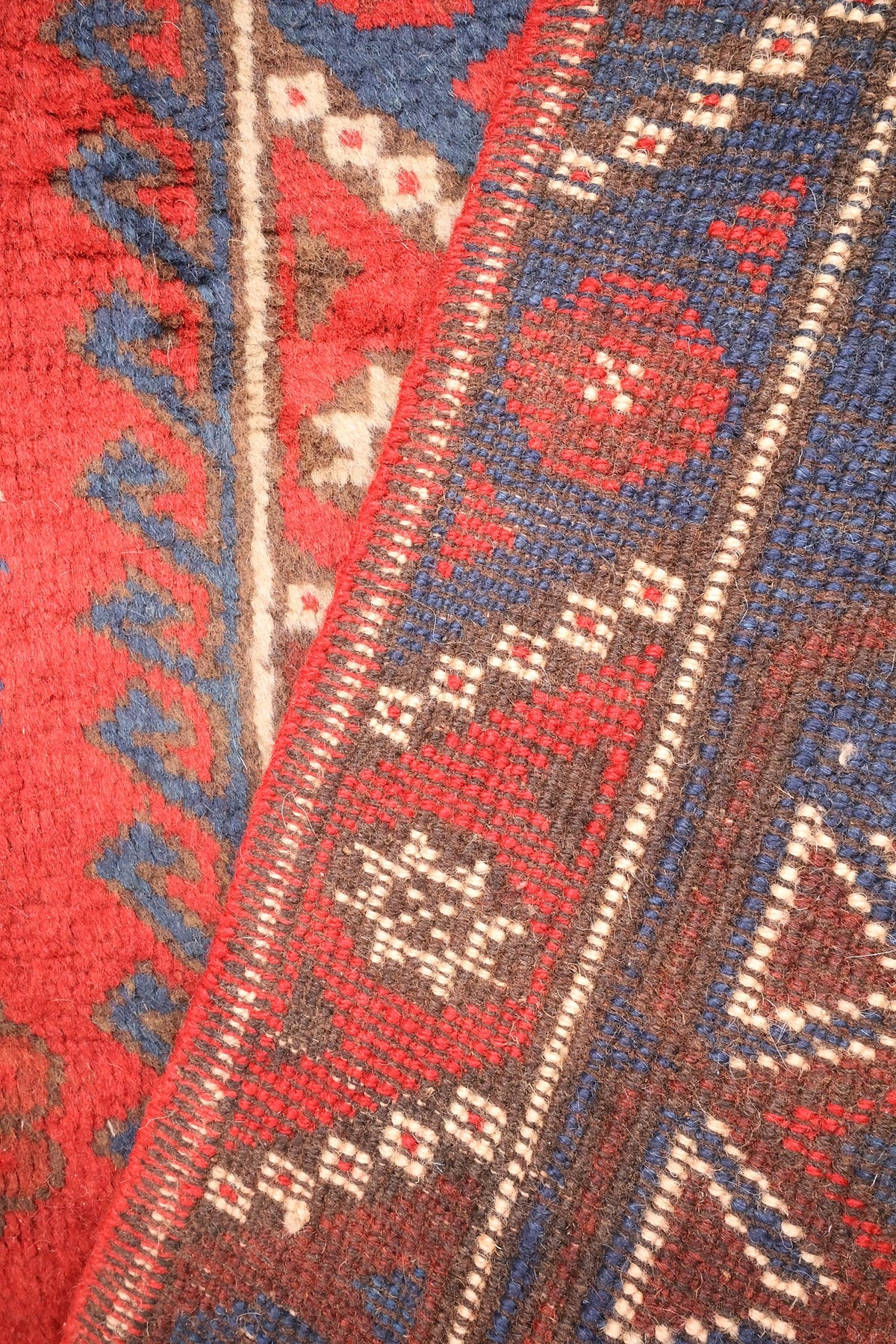 Coin replié du tapis Dodgem Alti, envers et nœuds visibles le long de la bordure
