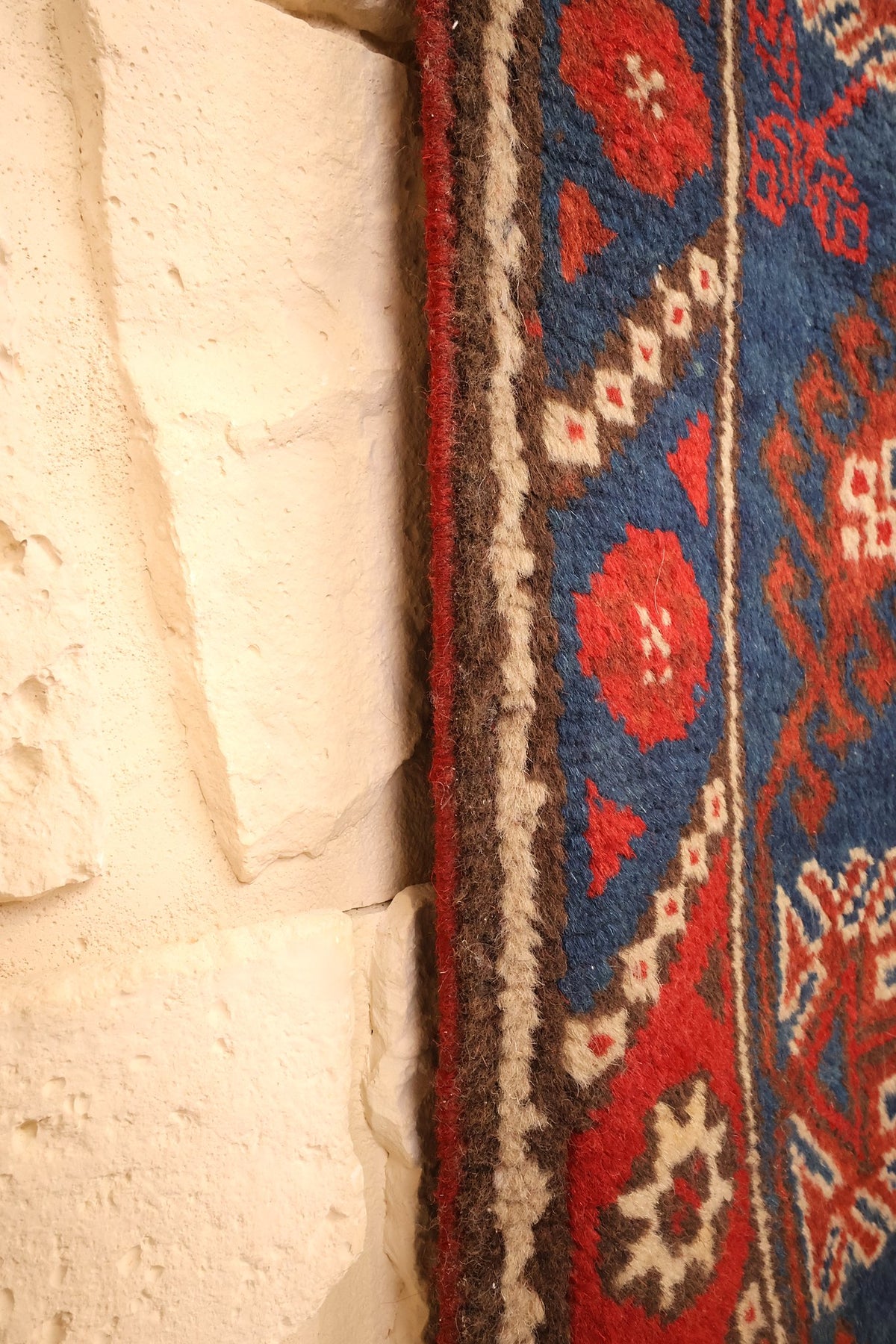 Lisière du tapis Dodgem Alti beige et brune, bordé du galon bleu à motifs rouges