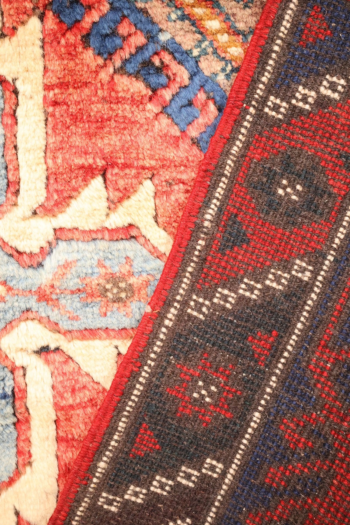 Envers du tapis Dodgem Alti, nœuds serrés et contours rouges, bleus et ivoire visibles