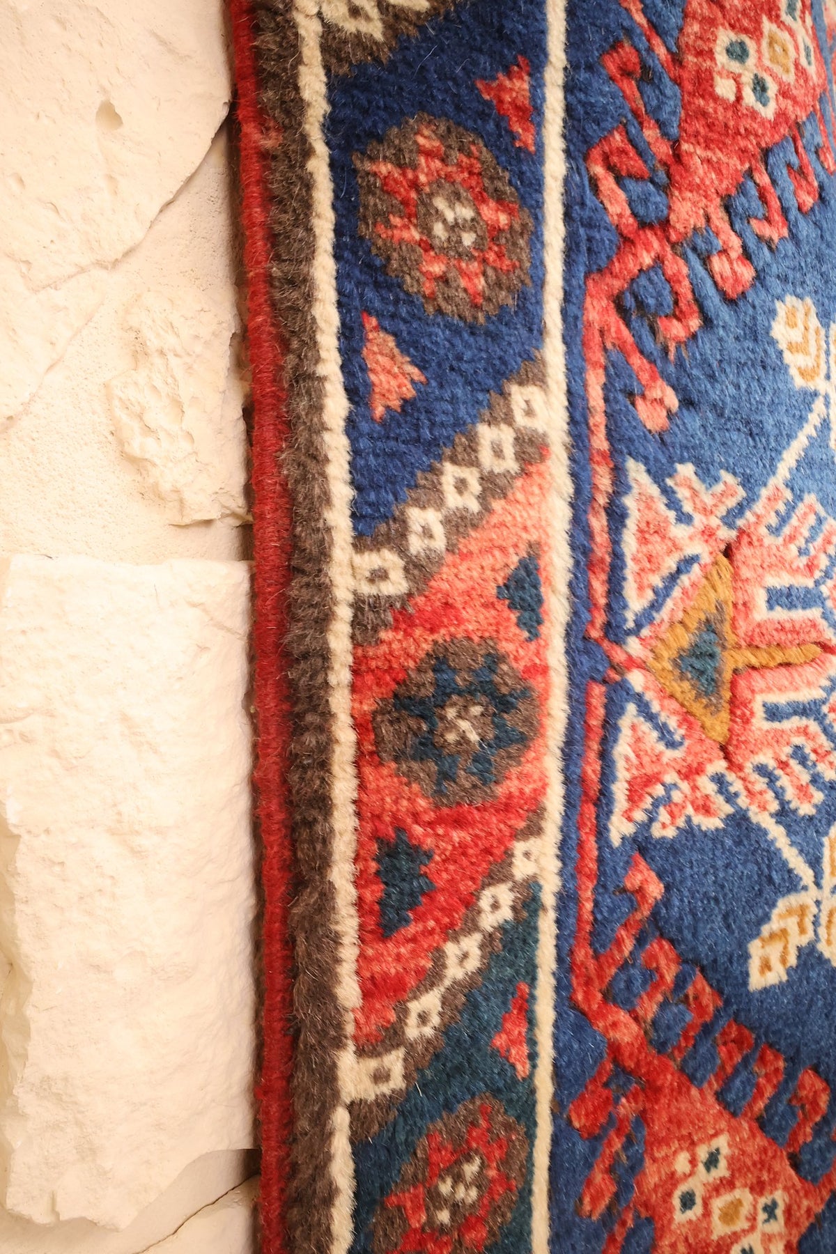 Lisière du tapis Dodgem Alti rouge et bleu longeant la bordure à losanges et rosaces