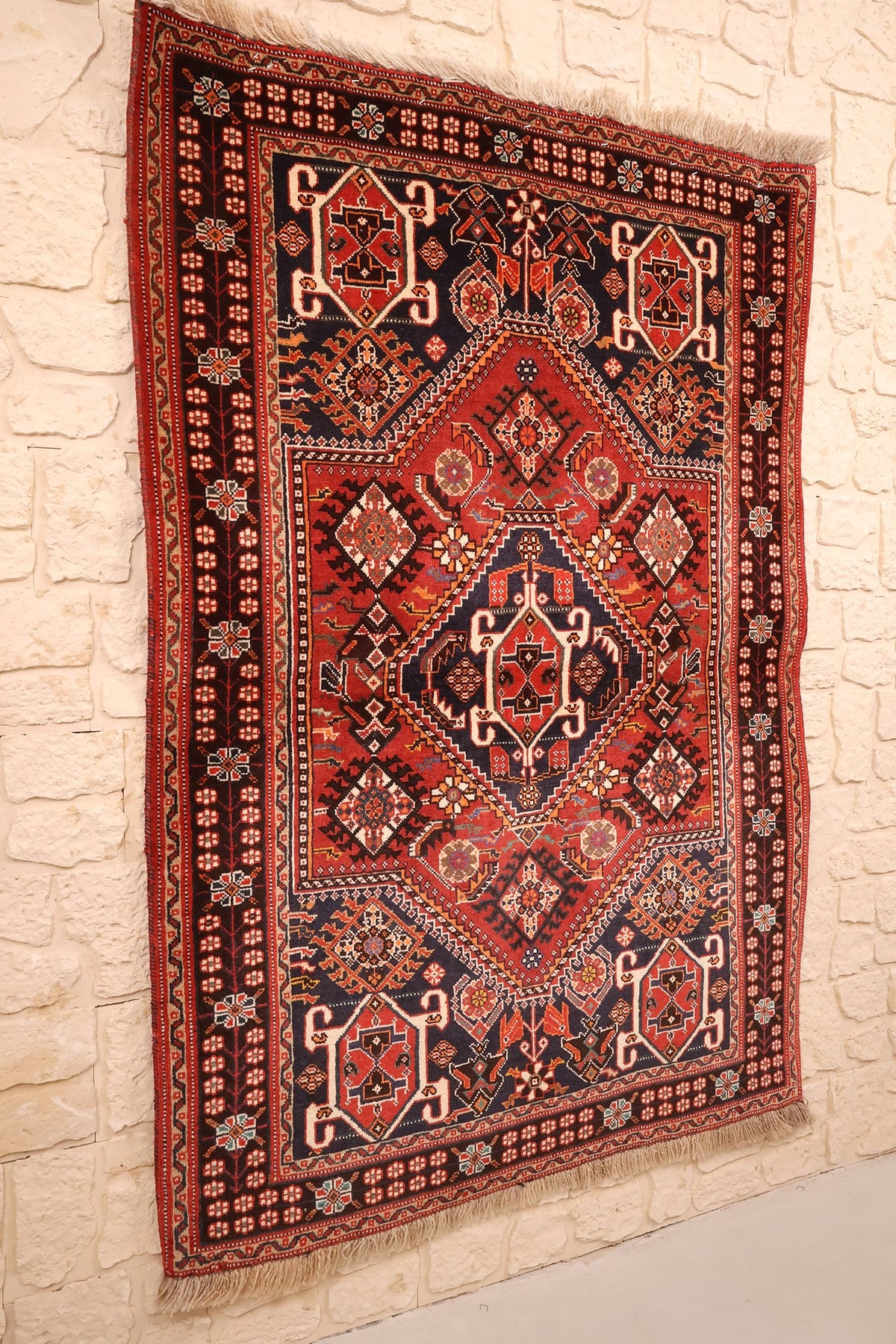 Tapis Gashgaï en laine noué à la main, vue de biais sur le champ rouge brique