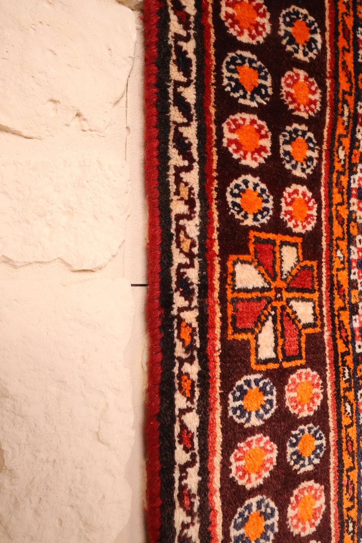Bord latéral du tapis Gashgaï rouge, rosettes orange sur fond brun foncé