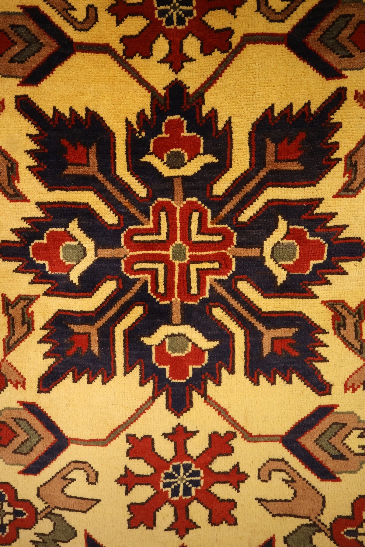 Détail du médaillon anguleux bleu nuit et rouge du tapis Ghazni jaune
