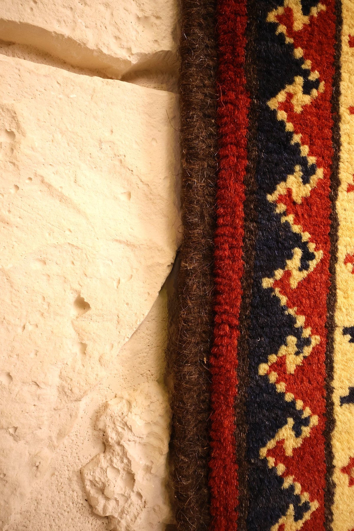 Lisière brune du tapis Ghazni, liseré rouge et motifs crochetés beiges