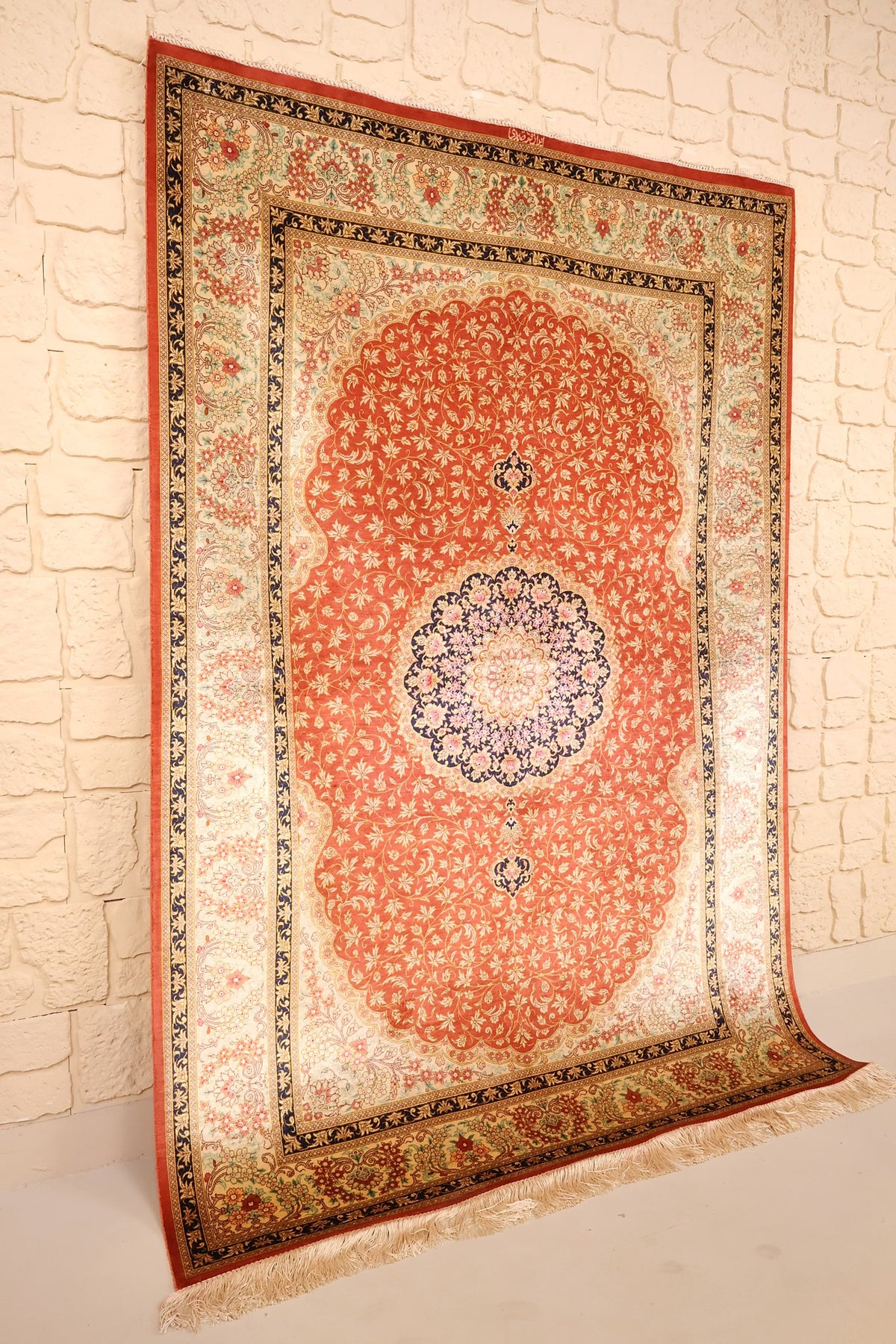 Tapis Ghoum rouge et beige vu de biais, bordure ivoire à guirlandes florales