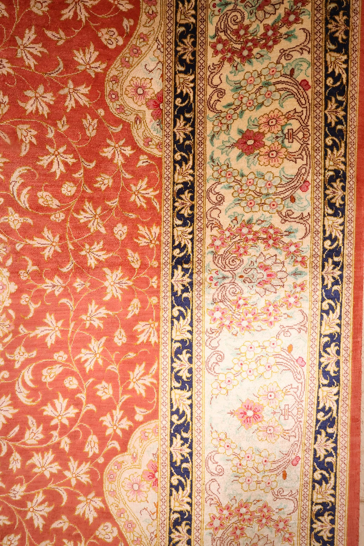 Bordure ivoire fleurie et contre-bordures bleu nuit du tapis Ghoum en soie