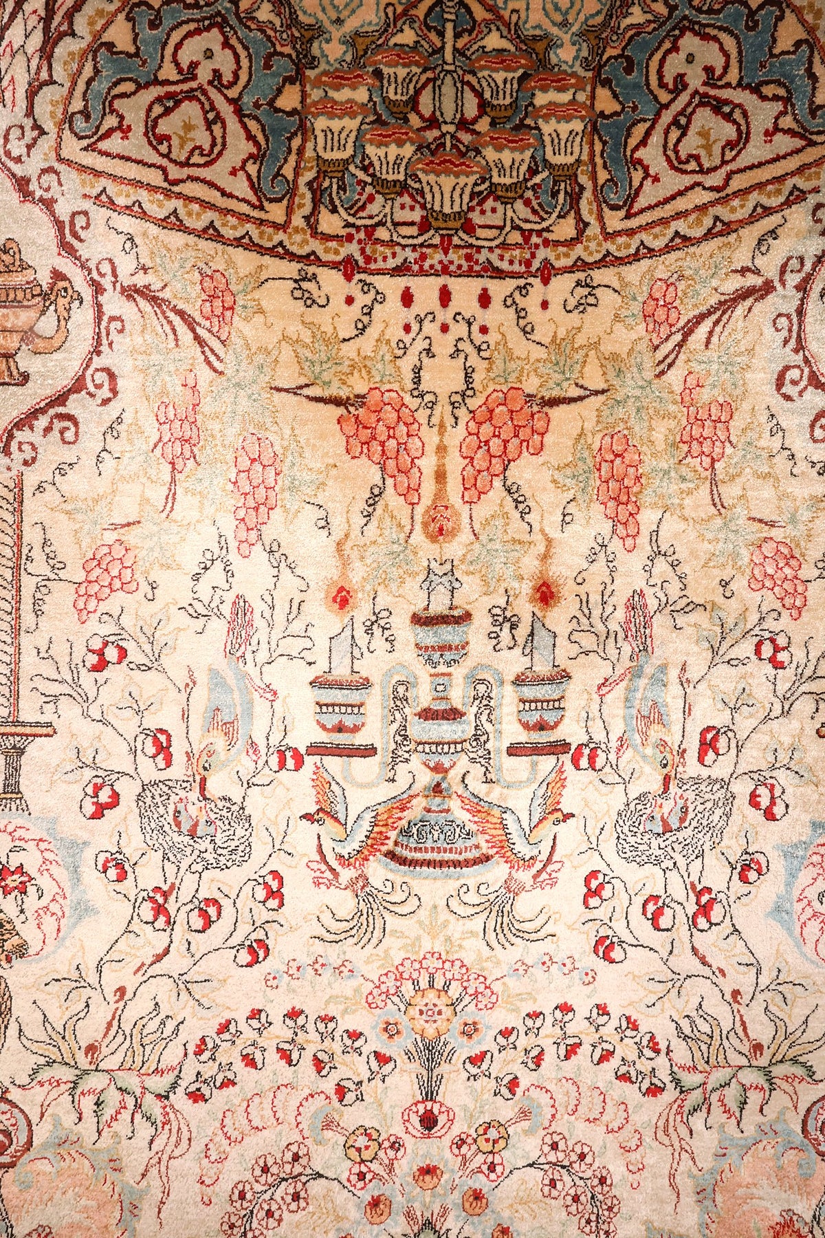 Détail du champ ivoire du tapis Ghoum : grappes de raisin roses, vases et oiseaux