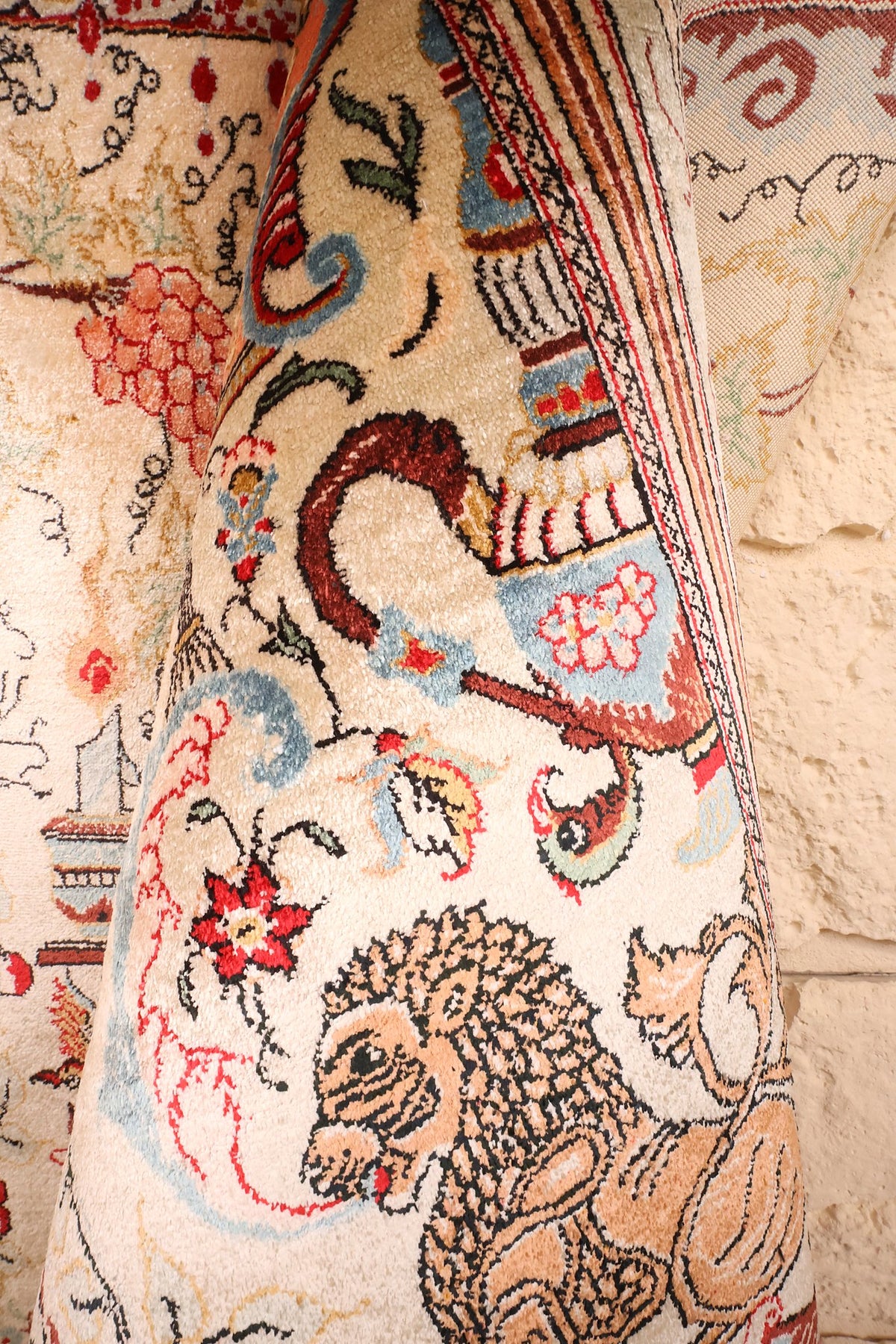 Coin replié du tapis Ghoum noué main, lion et rinceaux fleuris en soie