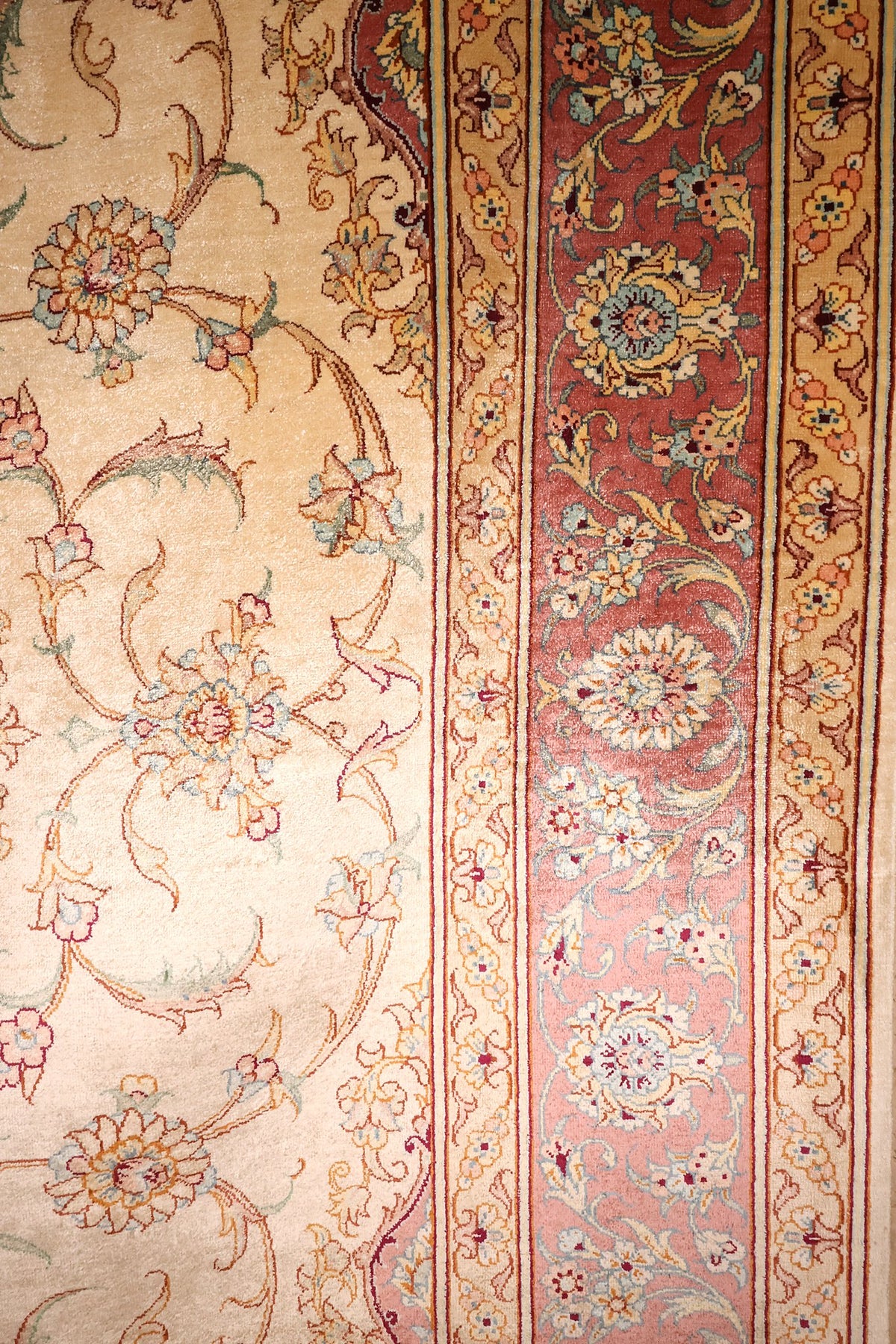 Bordure rouge brique à rinceaux fleuris et contre-bordures roses du tapis Ghoum
