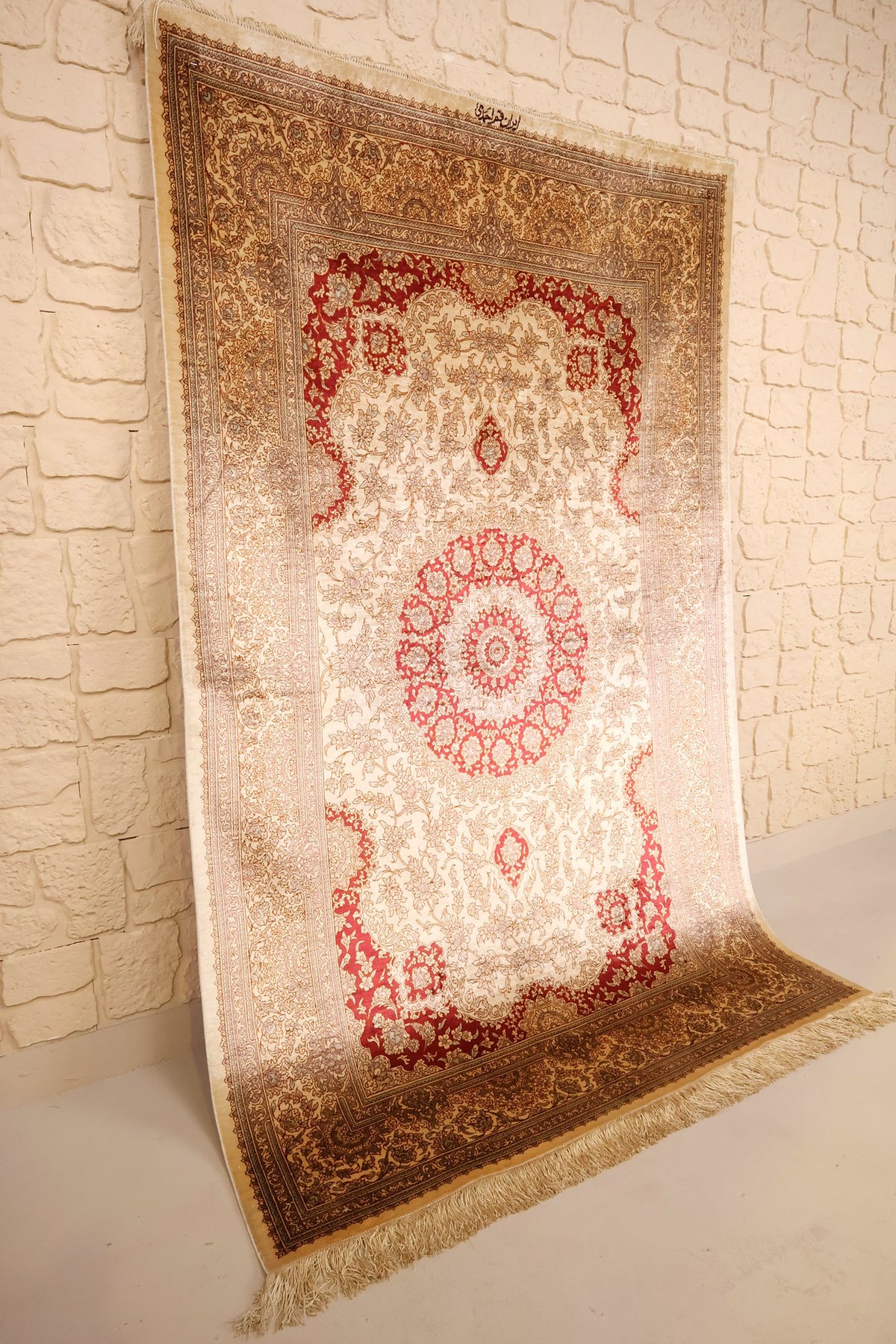 Tapis Ghoum beige et rouge 202 × 130 cm présenté de biais contre un mur clair
