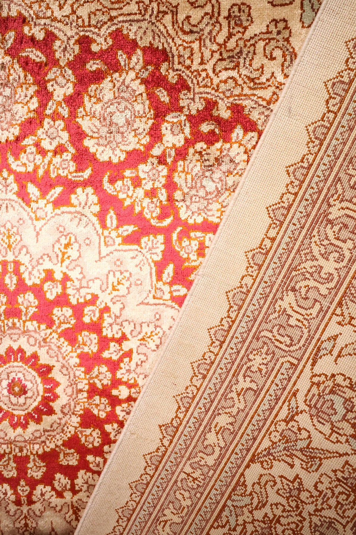 Gros plan du tapis Ghoum noué main, écoinçon rouge et bordure fleurie marron