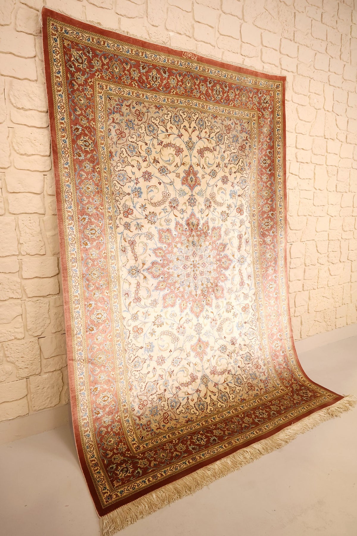 Tapis Ghoum en soie nouée main, vue de biais montrant le champ ivoire et les franges