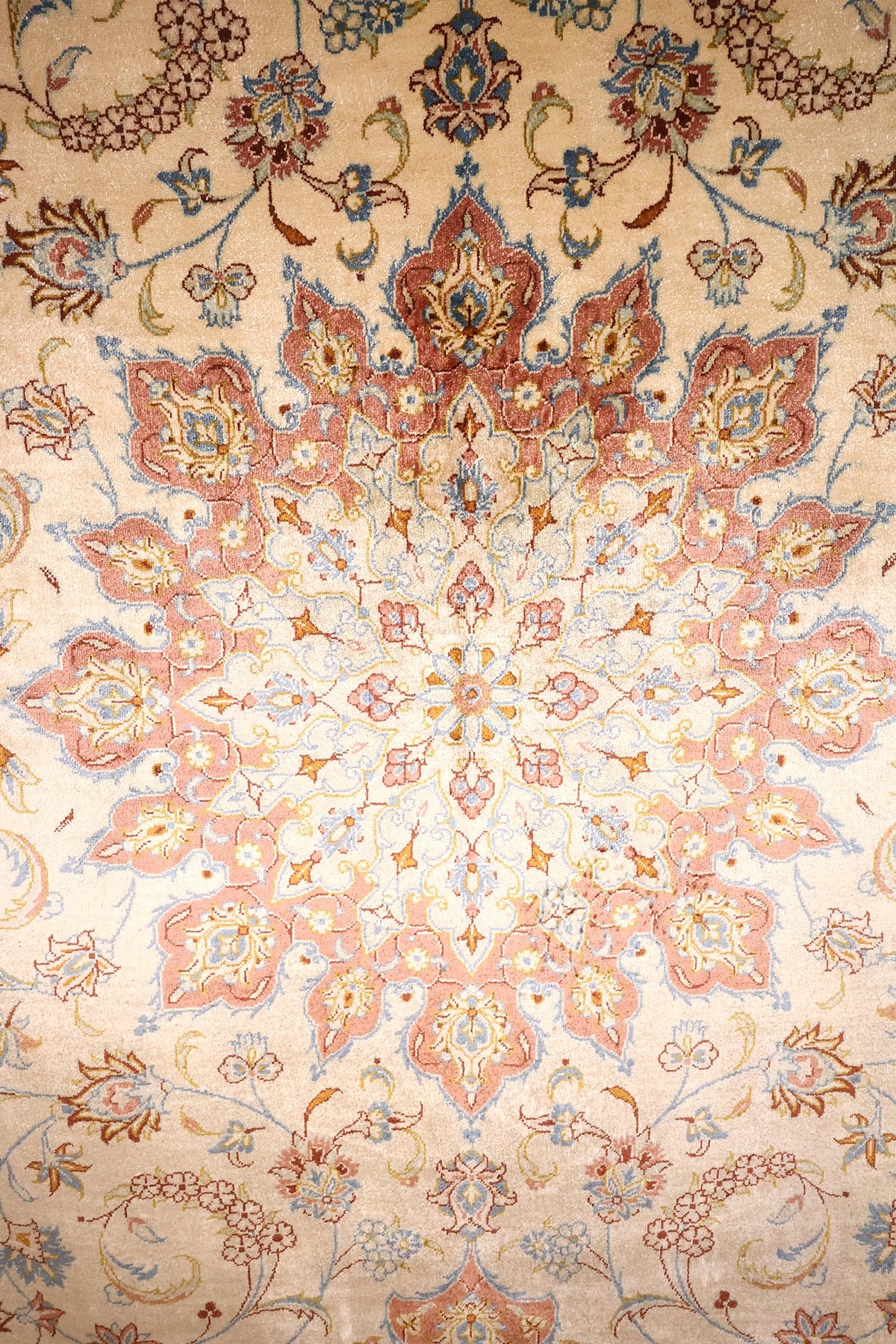 Détail du médaillon étoilé rose et des rinceaux fleuris du tapis Ghoum beige