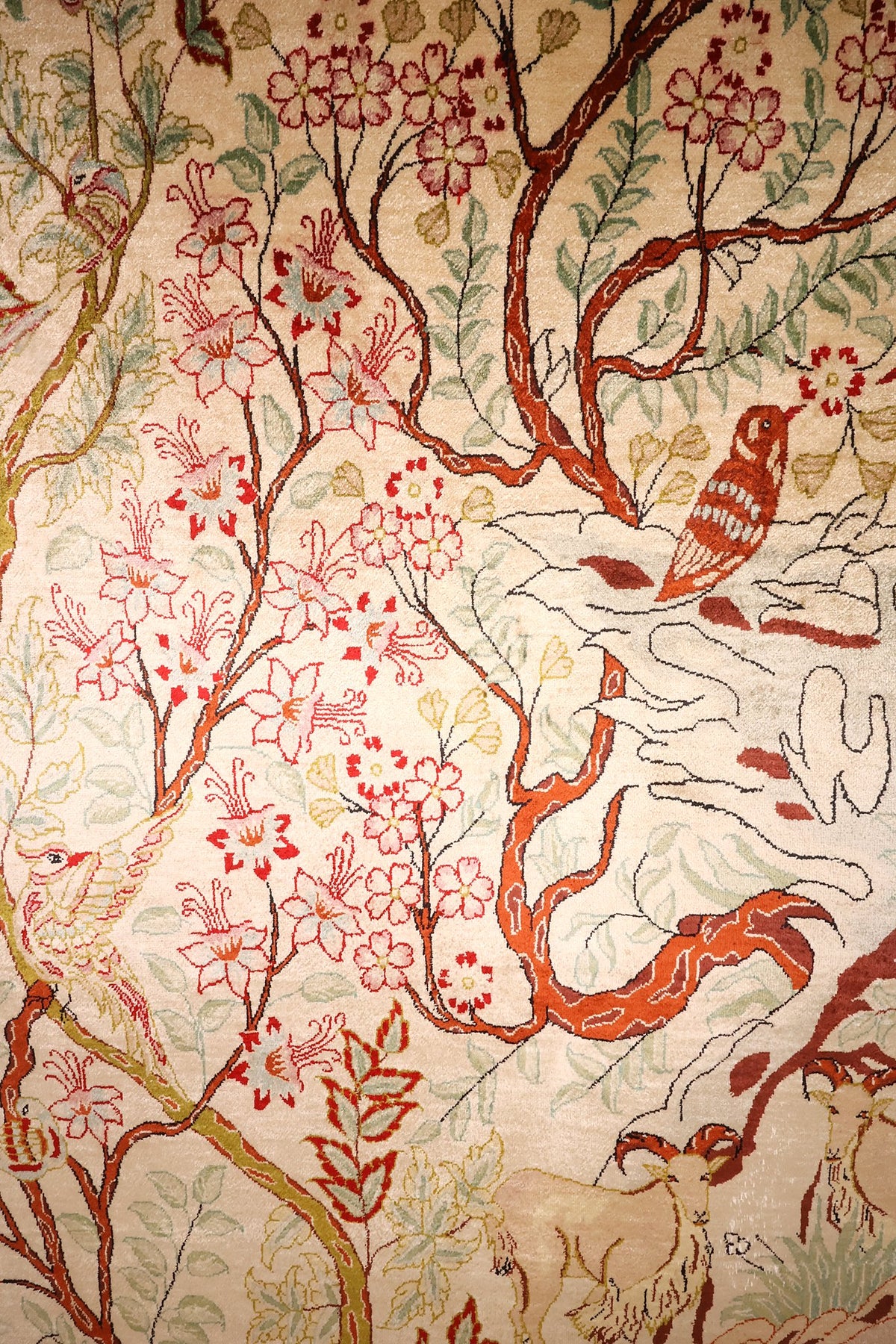 Détail des fleurs roses, de l'oiseau et des chèvres du tapis Ghoum en soie