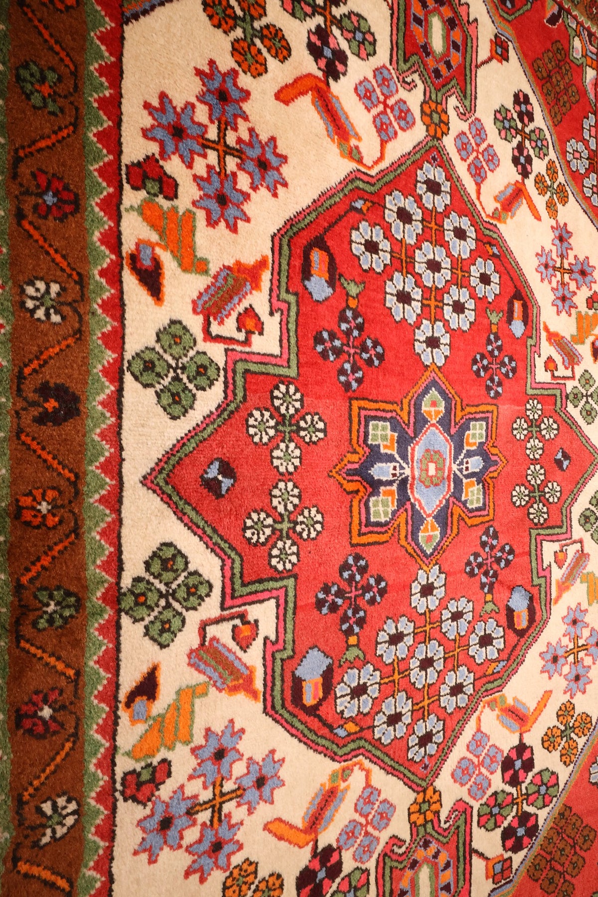 Gros plan du médaillon losangé bordé de crochets sur écoinçons beige du Hamadan