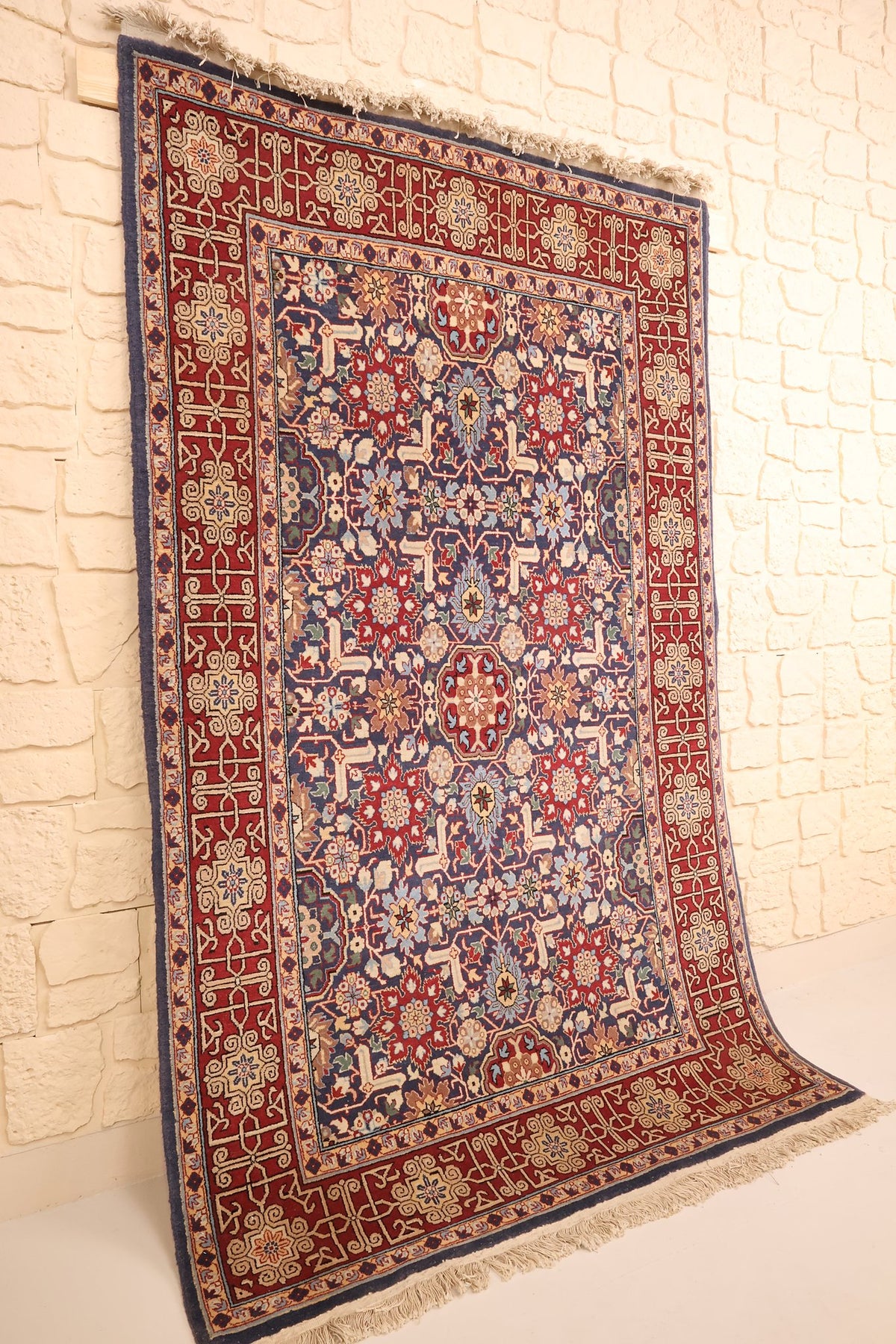 Tapis Hereke en laine nouée main, vue de biais contre un mur clair